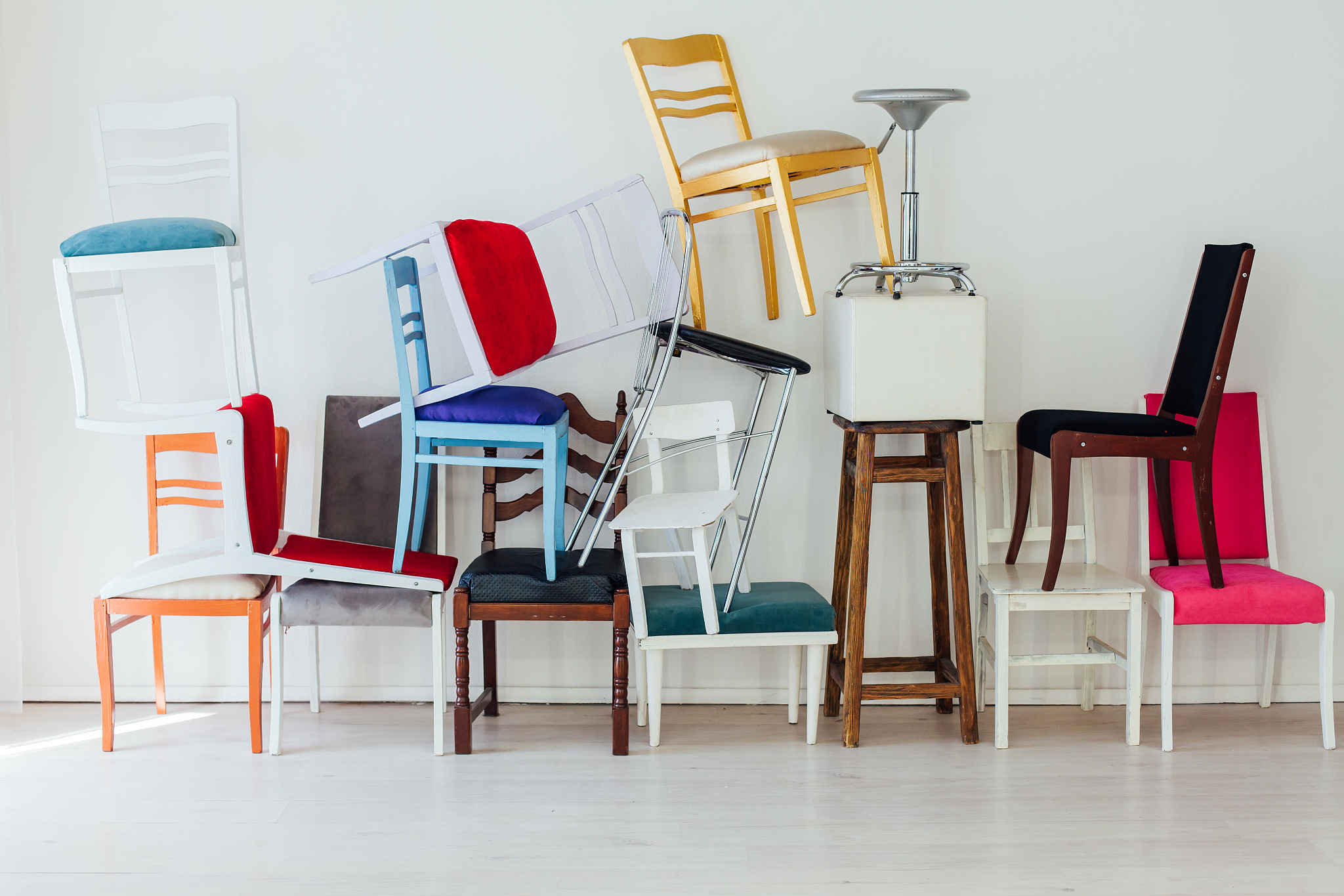 many different chairs stand in the white room