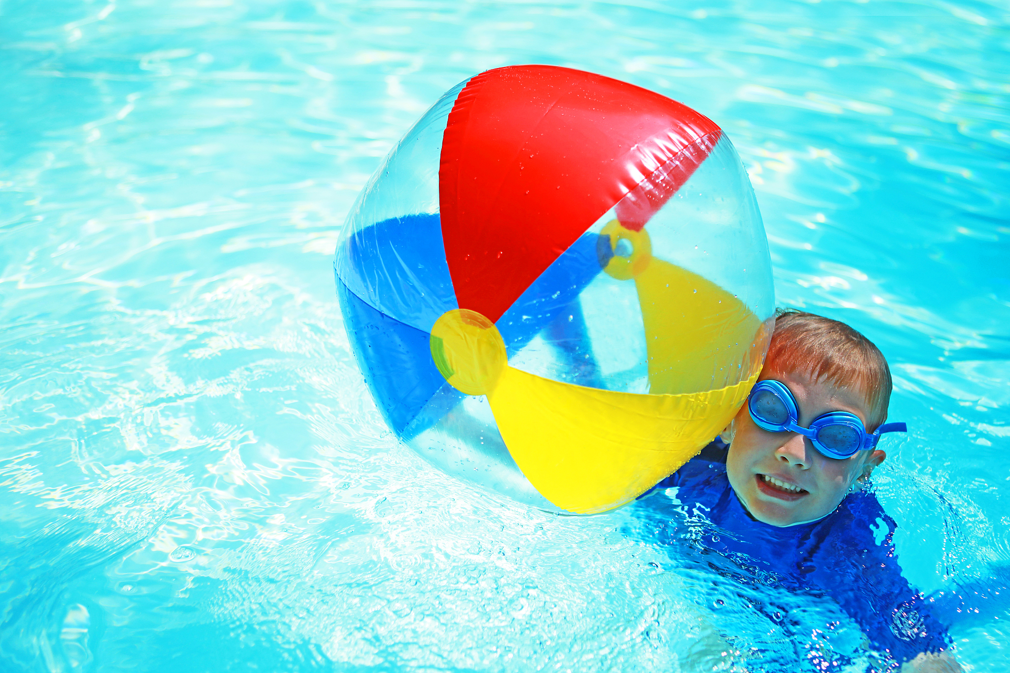 child holding colorful beach ball in swimming pool