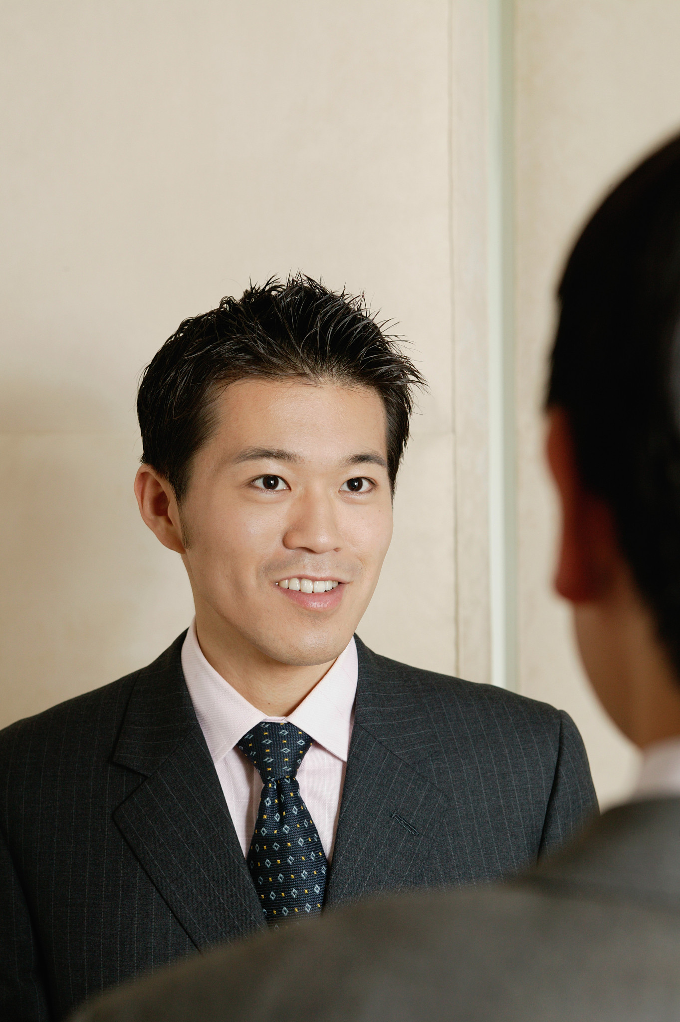 two businessmen indoors, facing each other (focus on one man)
