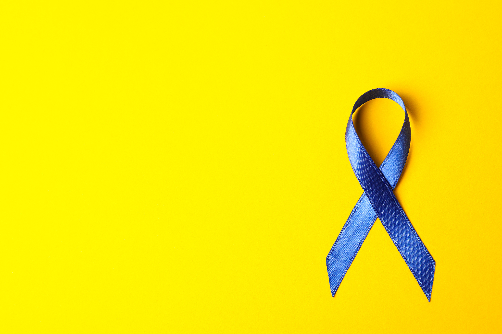 blue awareness ribbon on yellow background, space for text