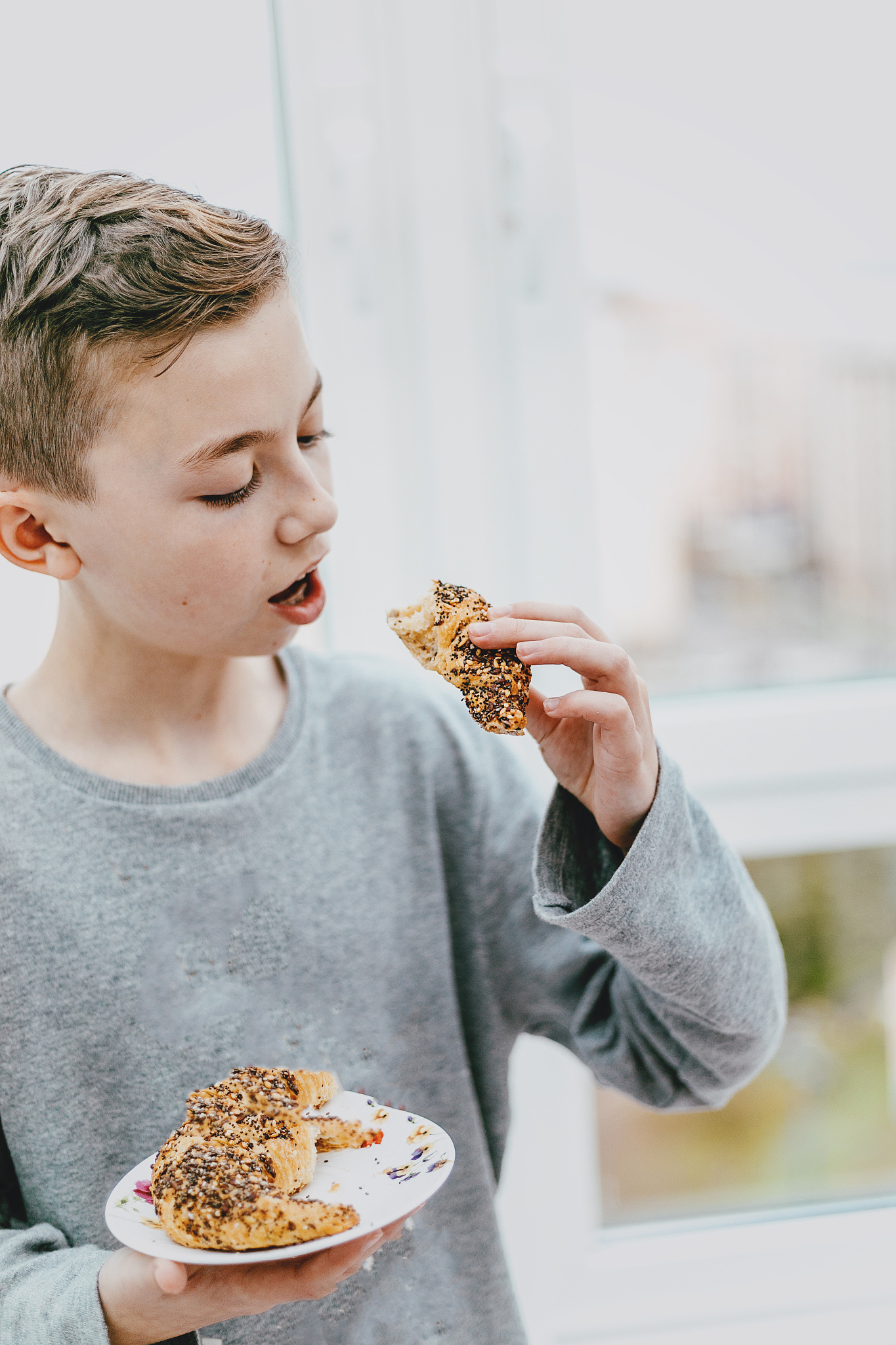 portrait happy, smiling boy choosing junk food.croissant