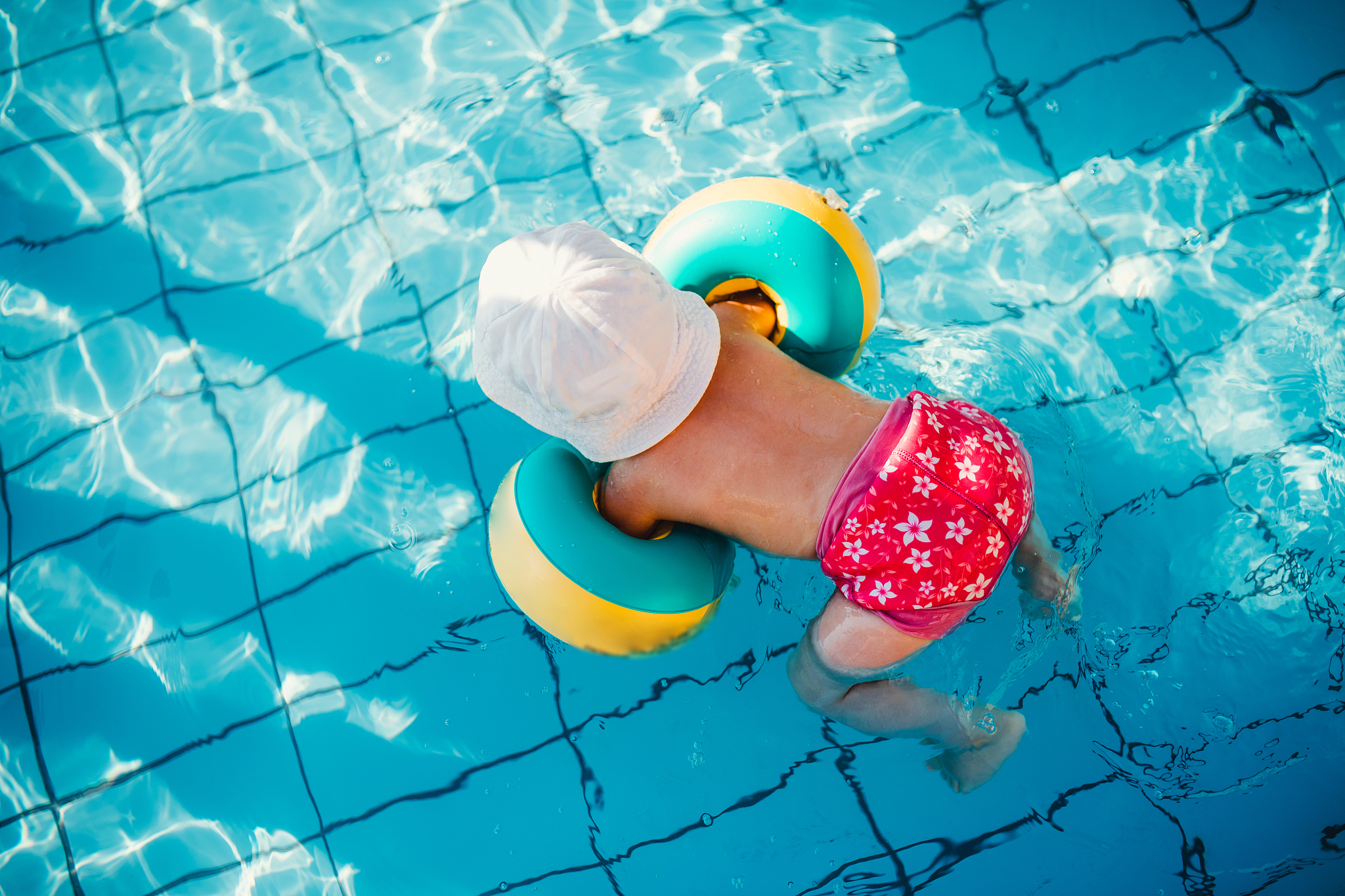 top view of small child with armbands in swimming pool on summer