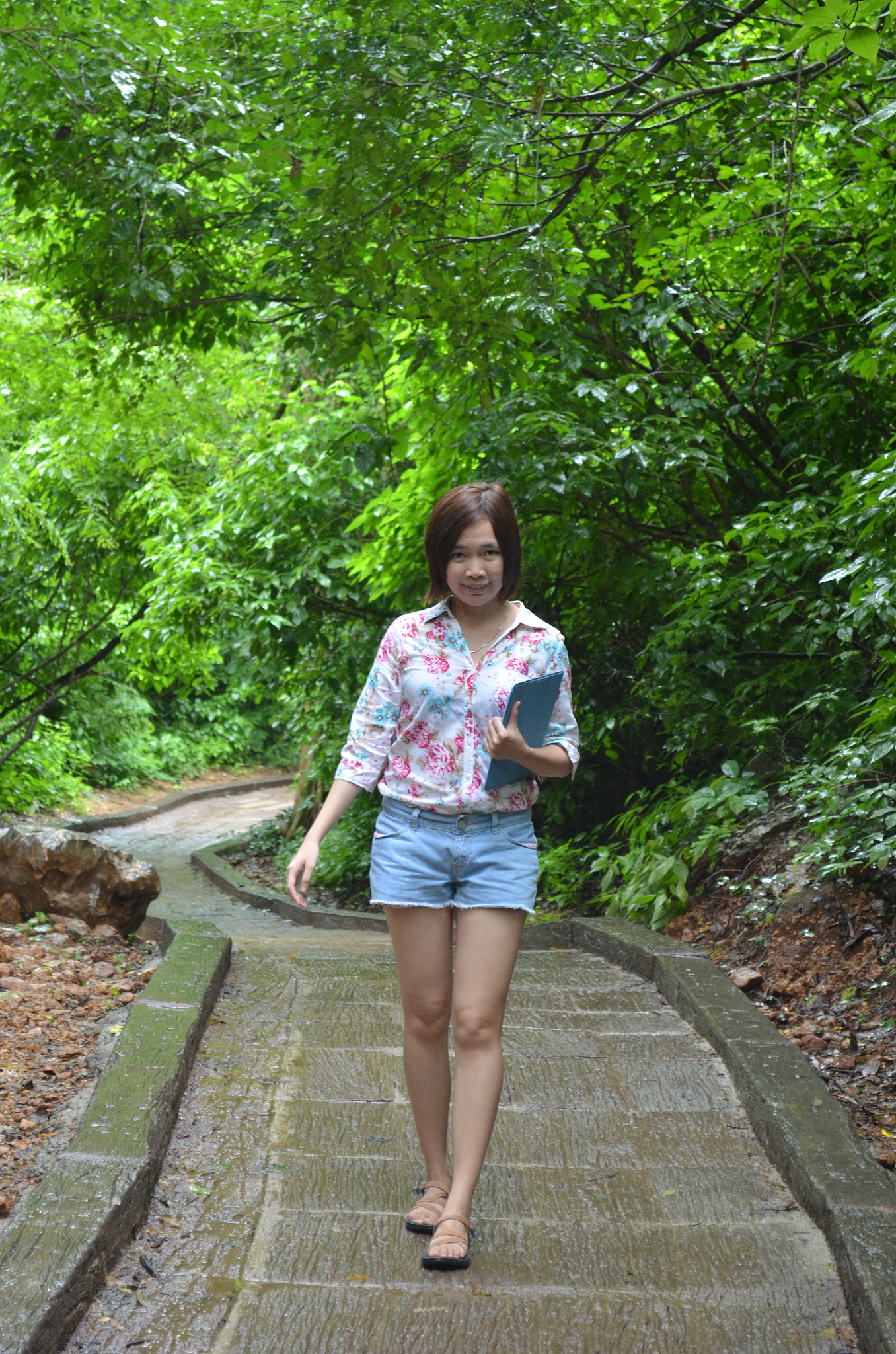 portrait of woman walking on footpath against trees