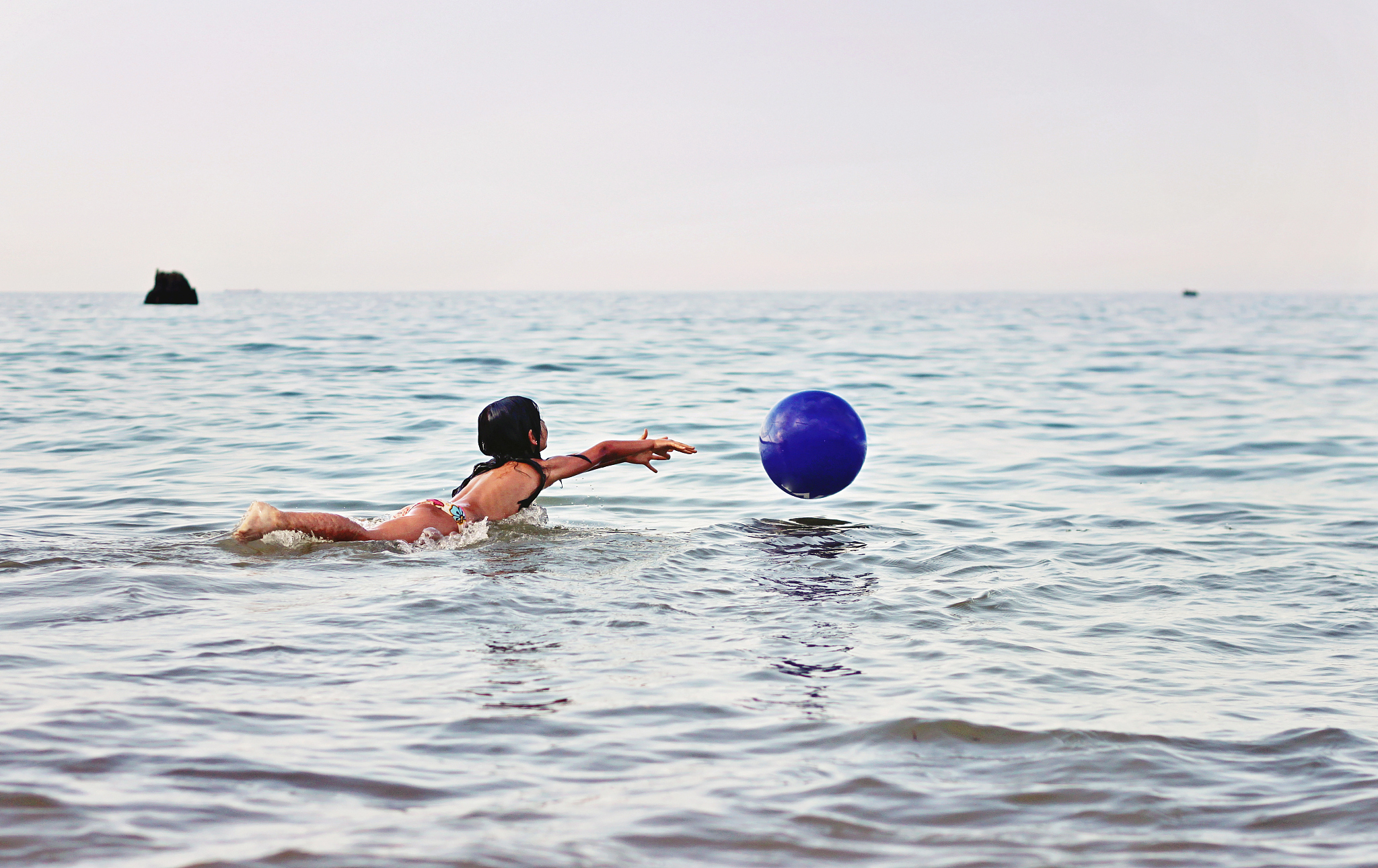 ocean. girl playing with ball in the blue sea.