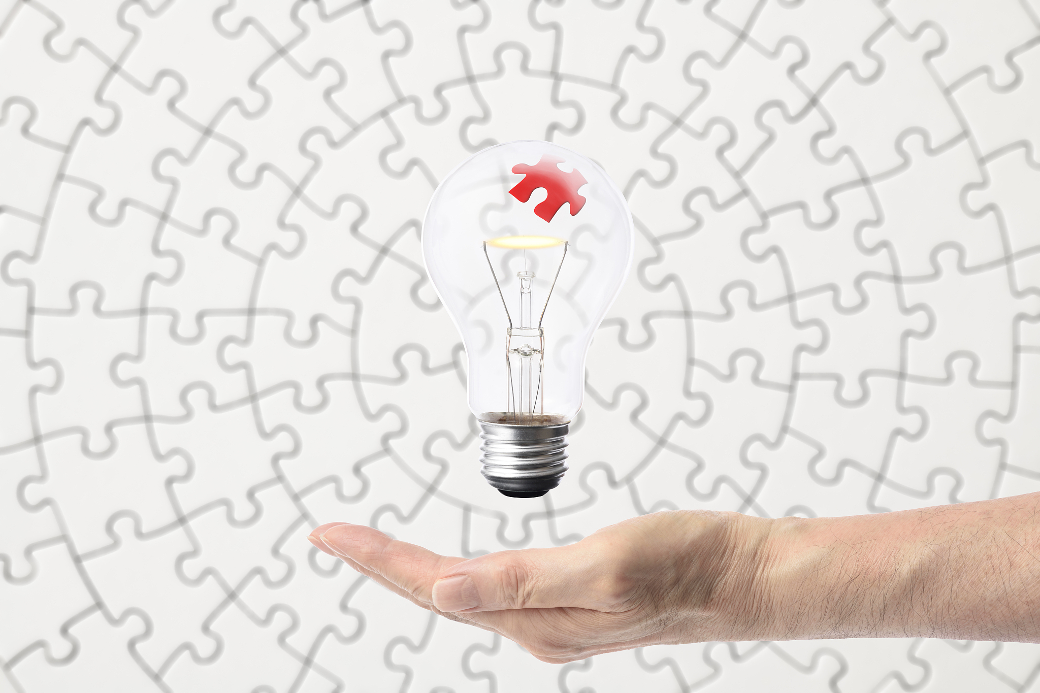 jigsaw puzzle inside the light bulb floating on the hand