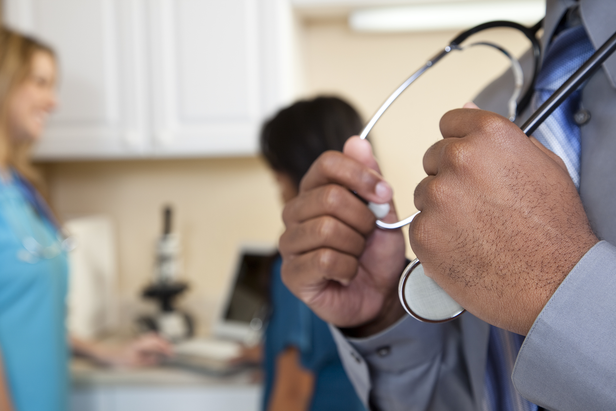 close-up of doctor's hands with other medical personnel in backg