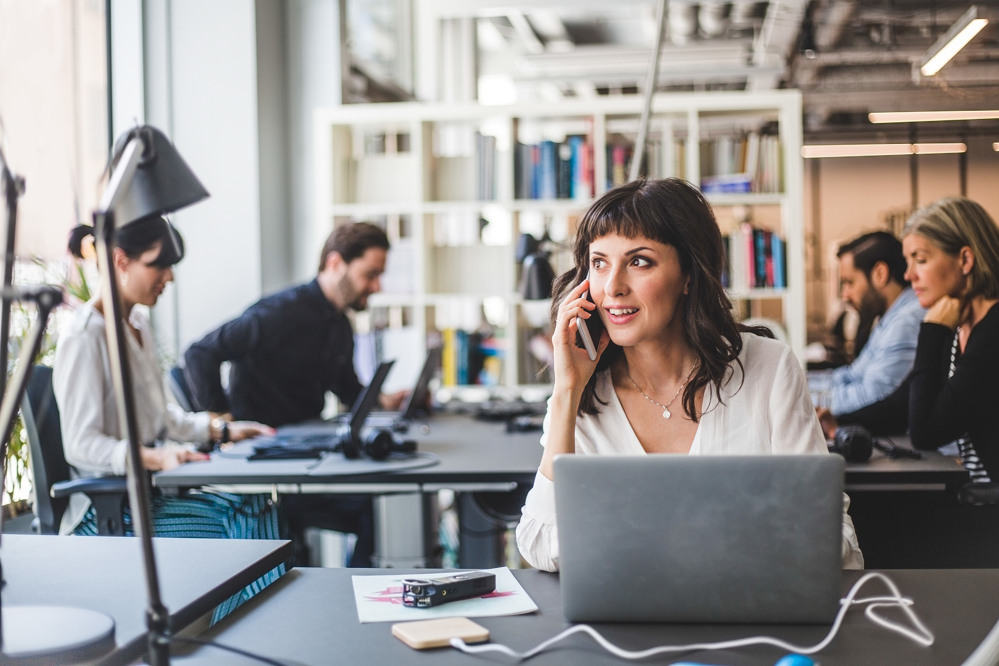 businesswoman looking away while talking on mobile phone at desk