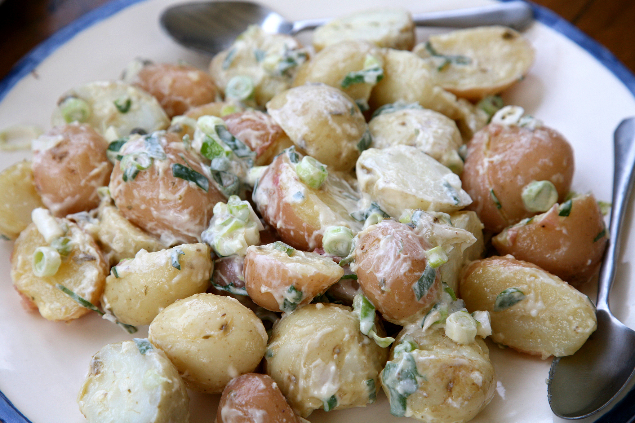 closeup of whole potato salad on a white plate with a spoon