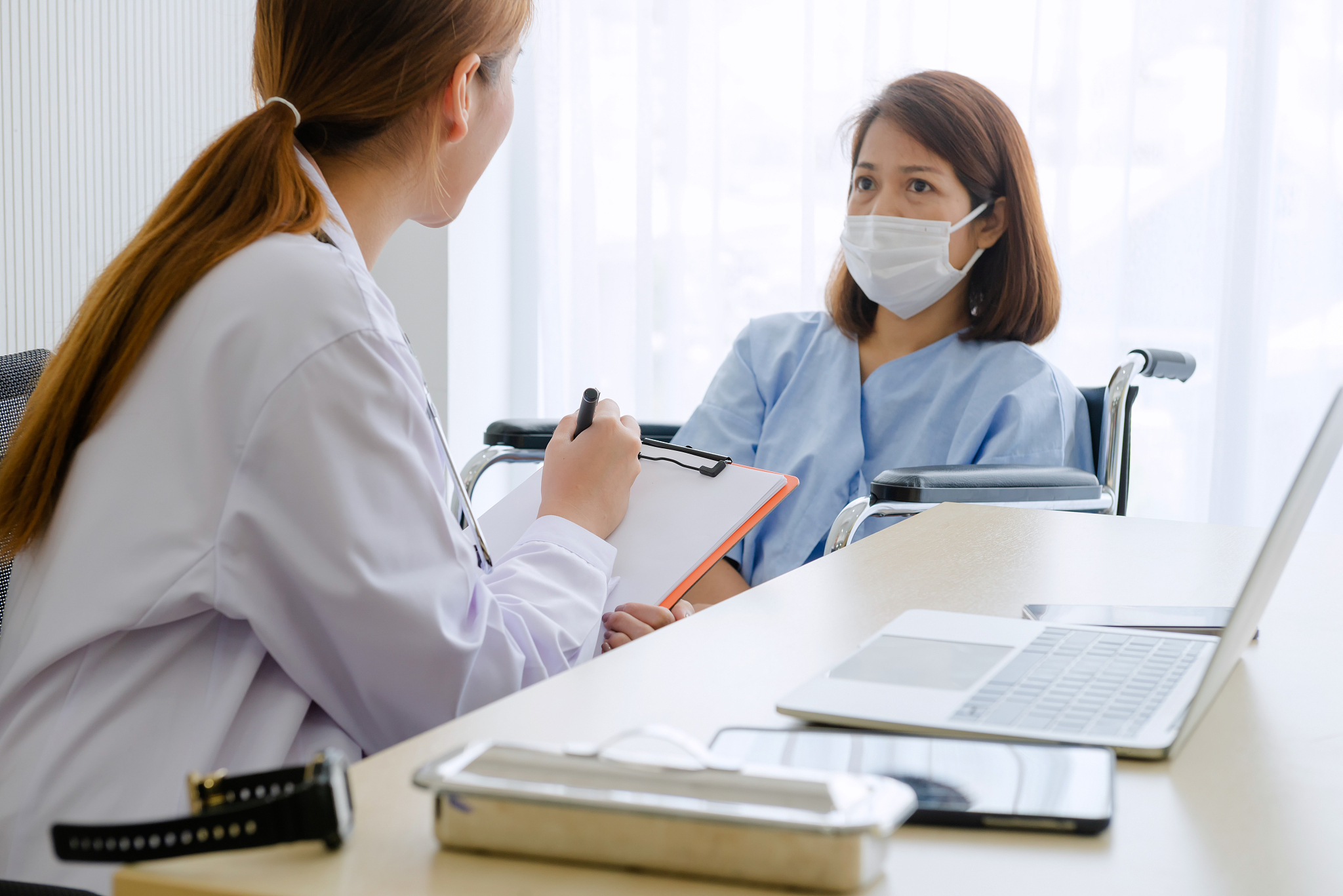 doctor talking to female patient in working cabinet at hospital