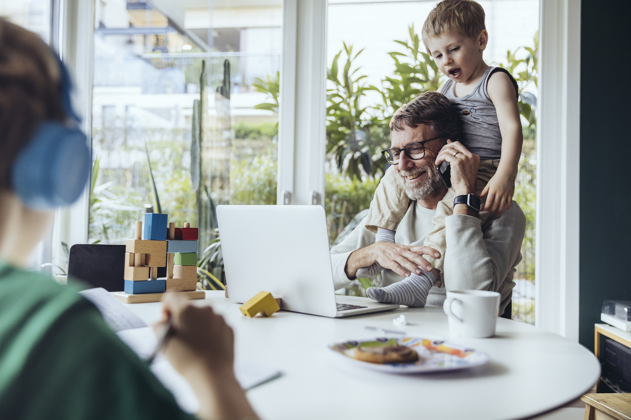 father working from home, talking on the phone, while children a