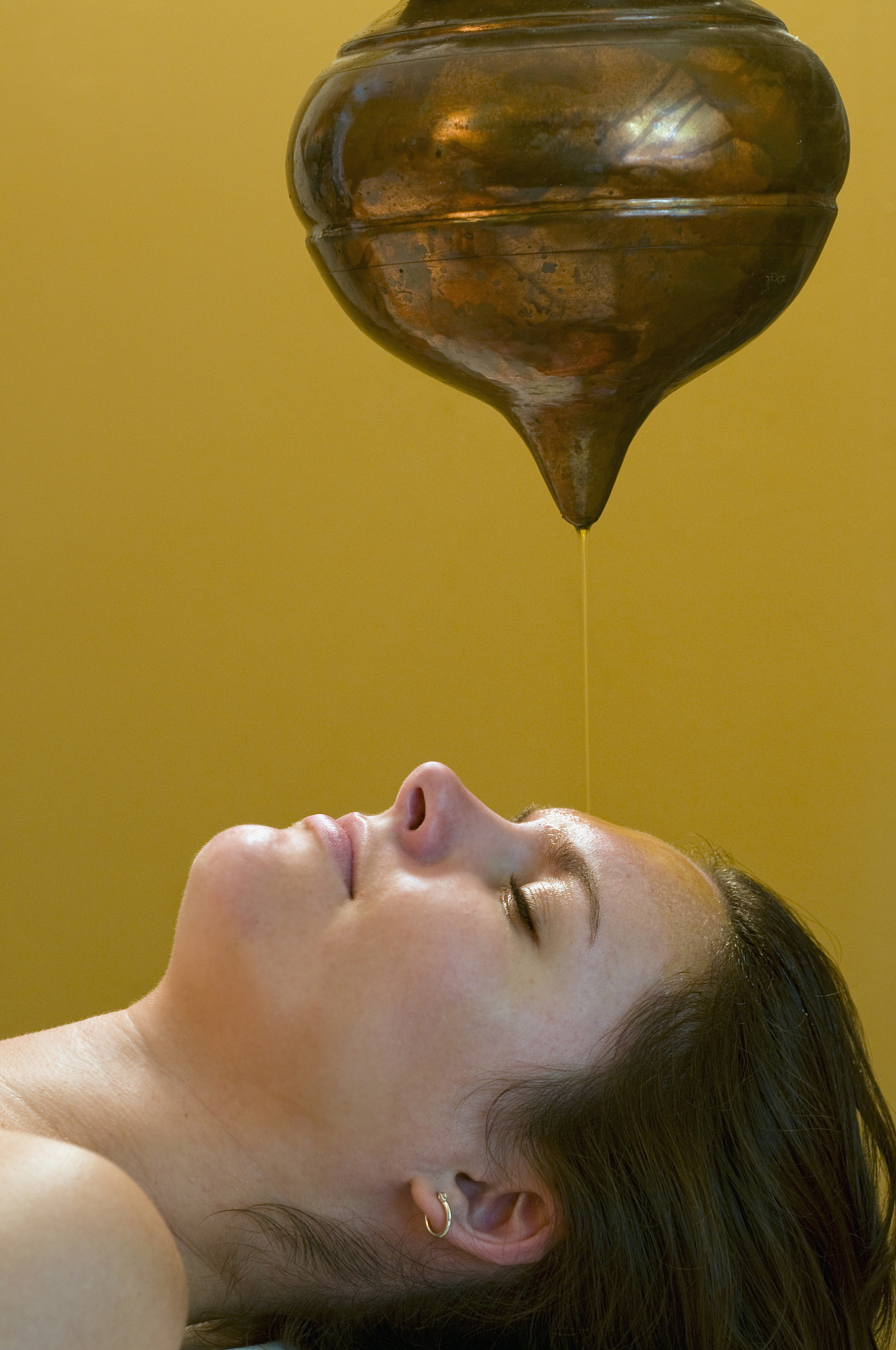 woman receives holistic shirodhara third-eye oil drip treatment