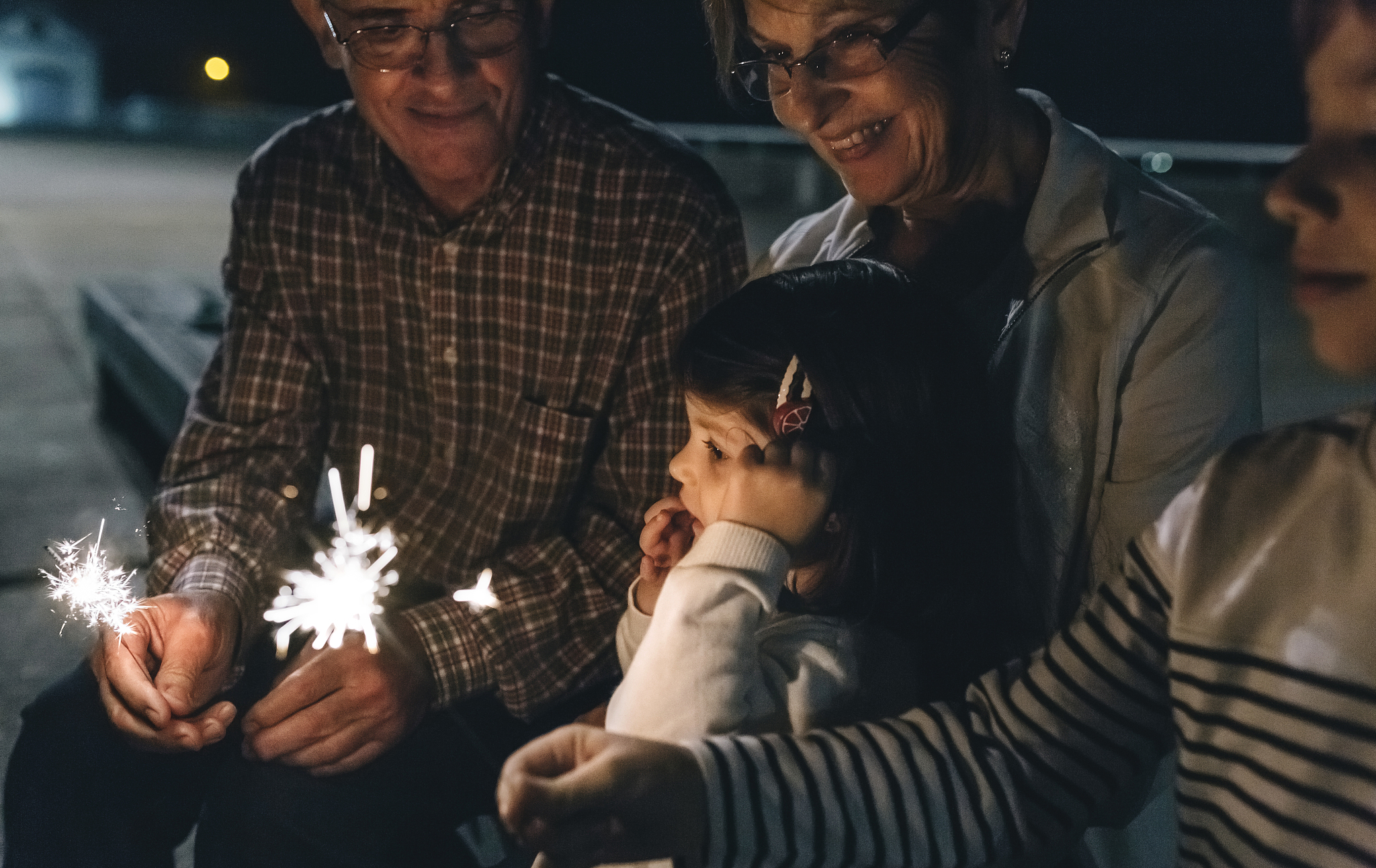 grandparents with grandchildren holding sparklers at night