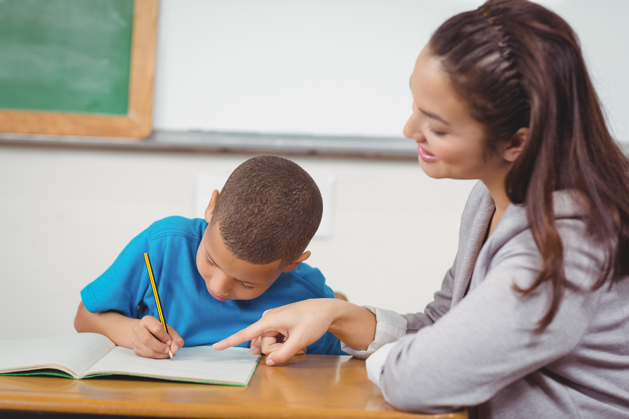 pretty teacher helping pupil at his desk