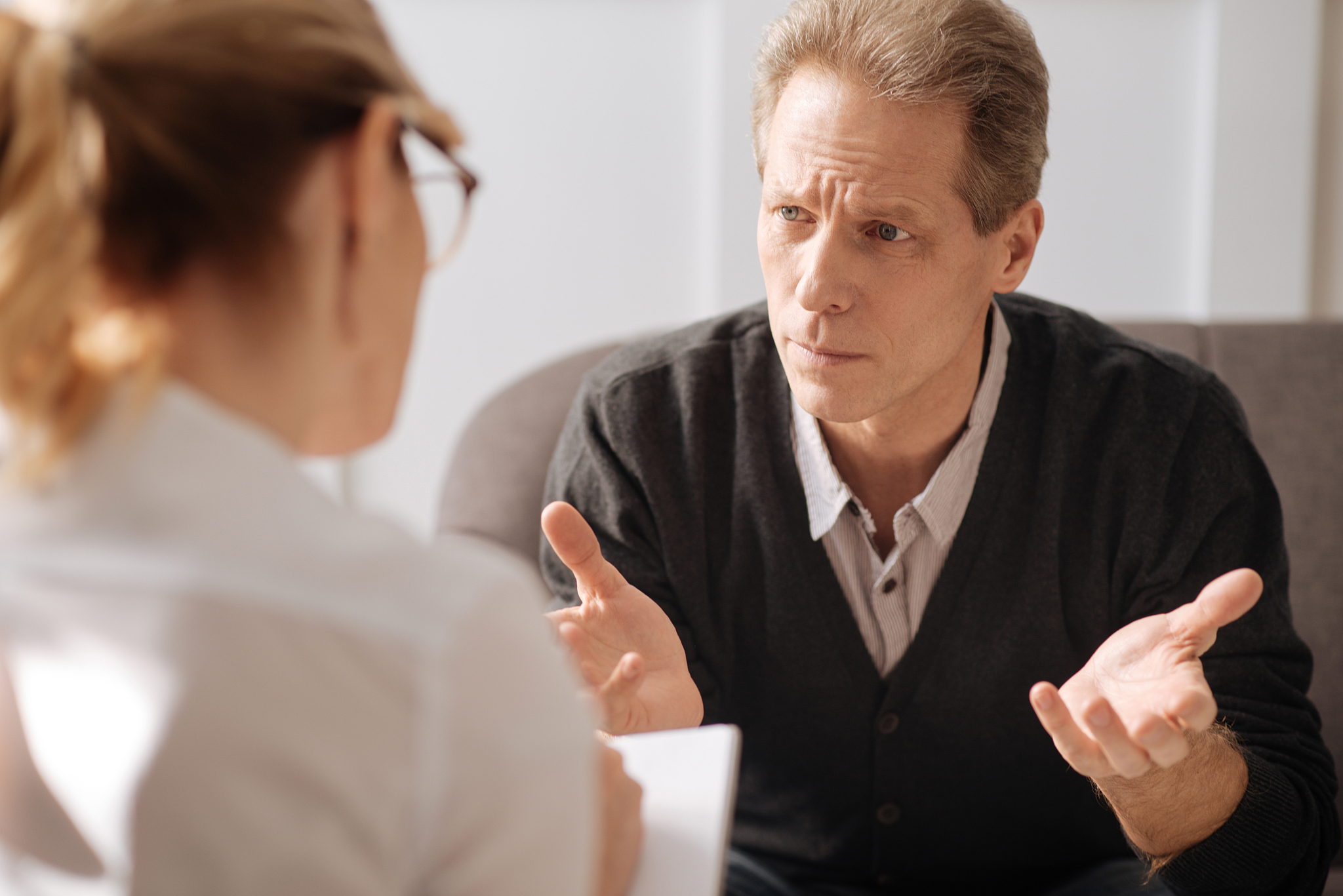 sad miserable man looking at his therapist