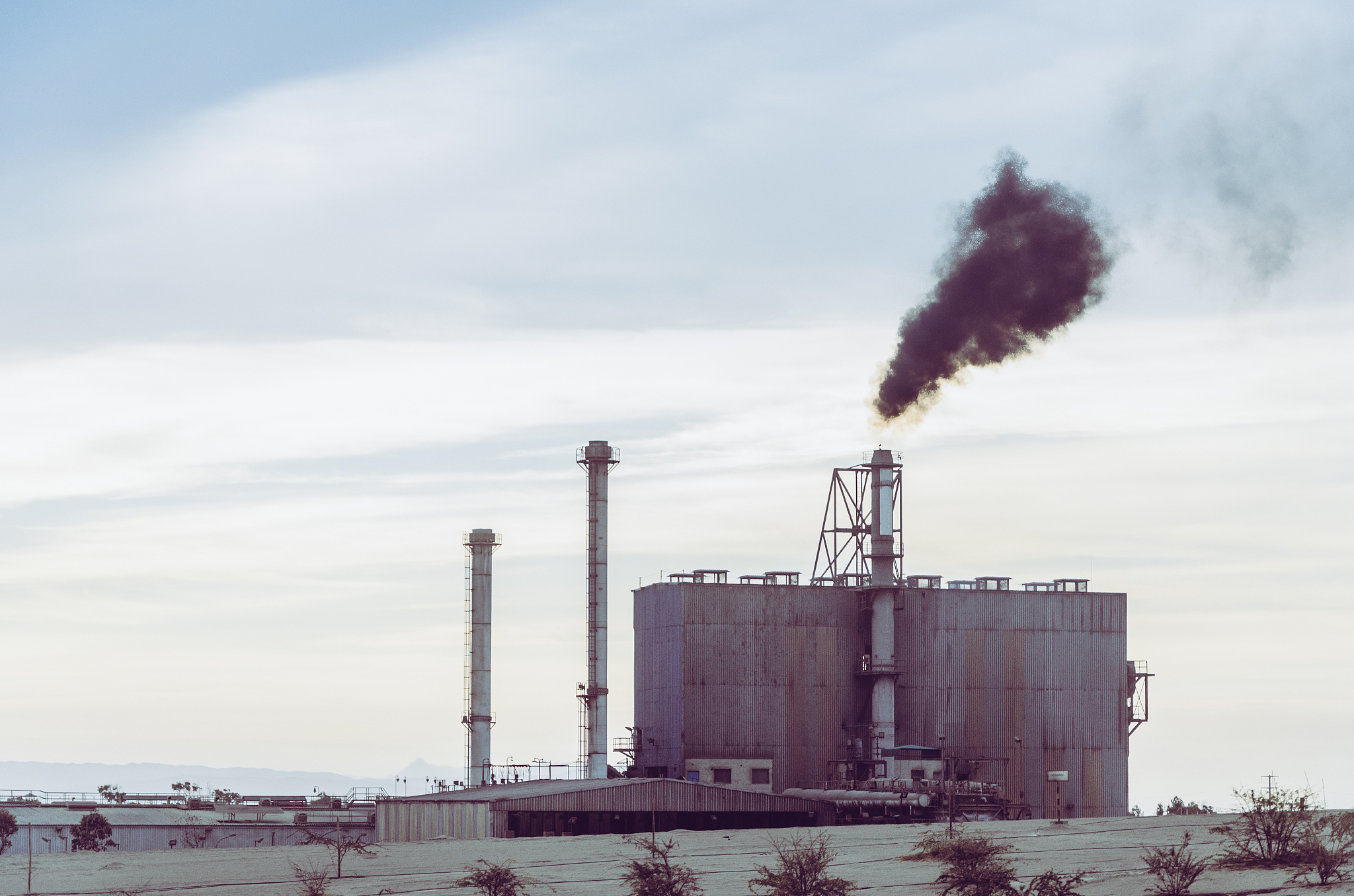 a factory is blowing smoke into the sky during the morning