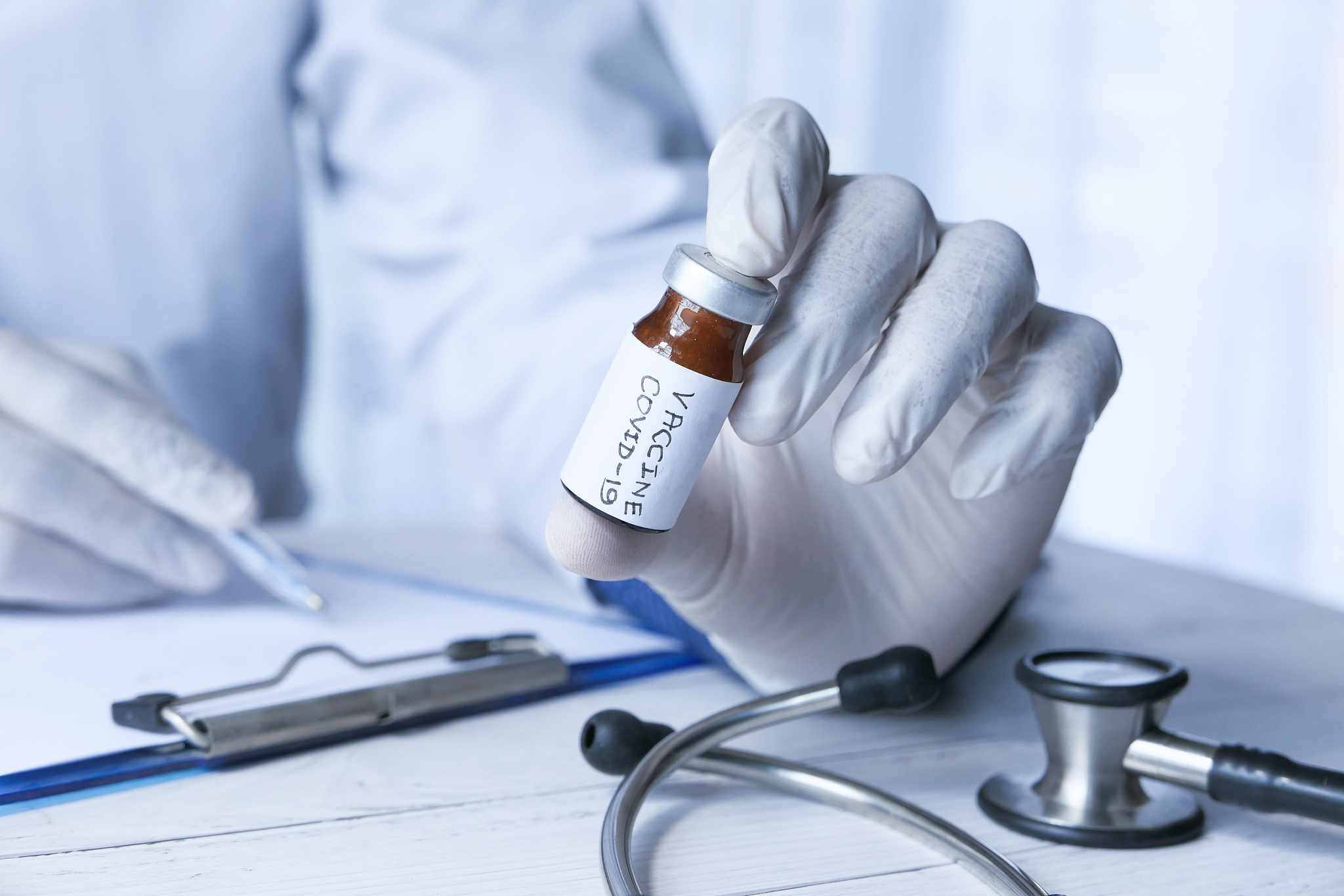 hand in gloves holding coronavirus, vaccine, close up