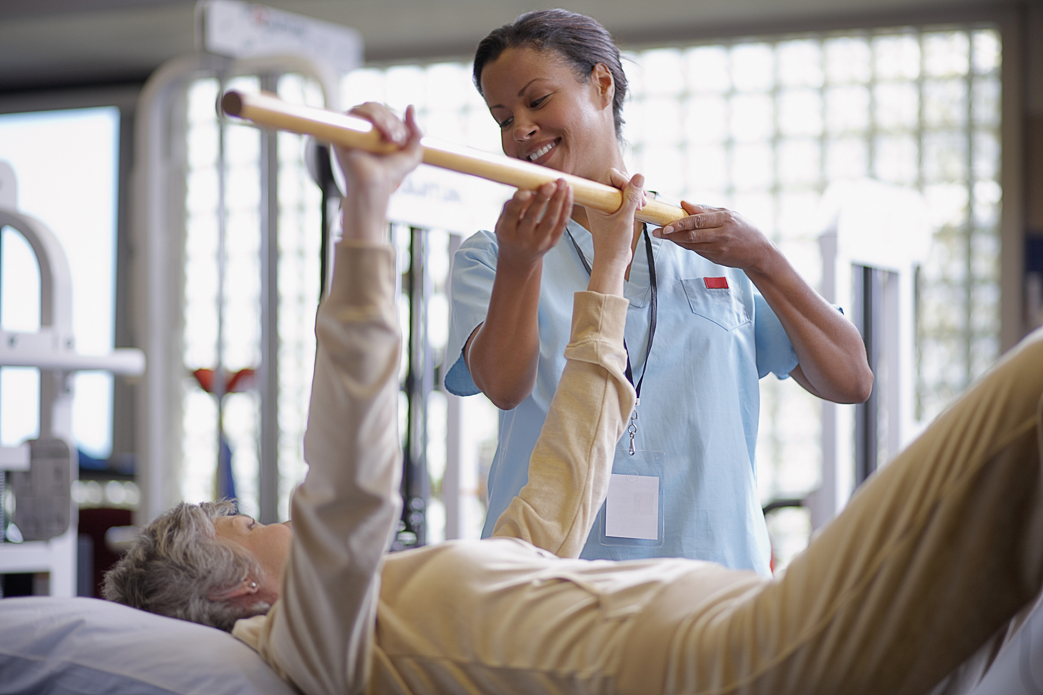 nurse helping middle aged woman with physical therapy