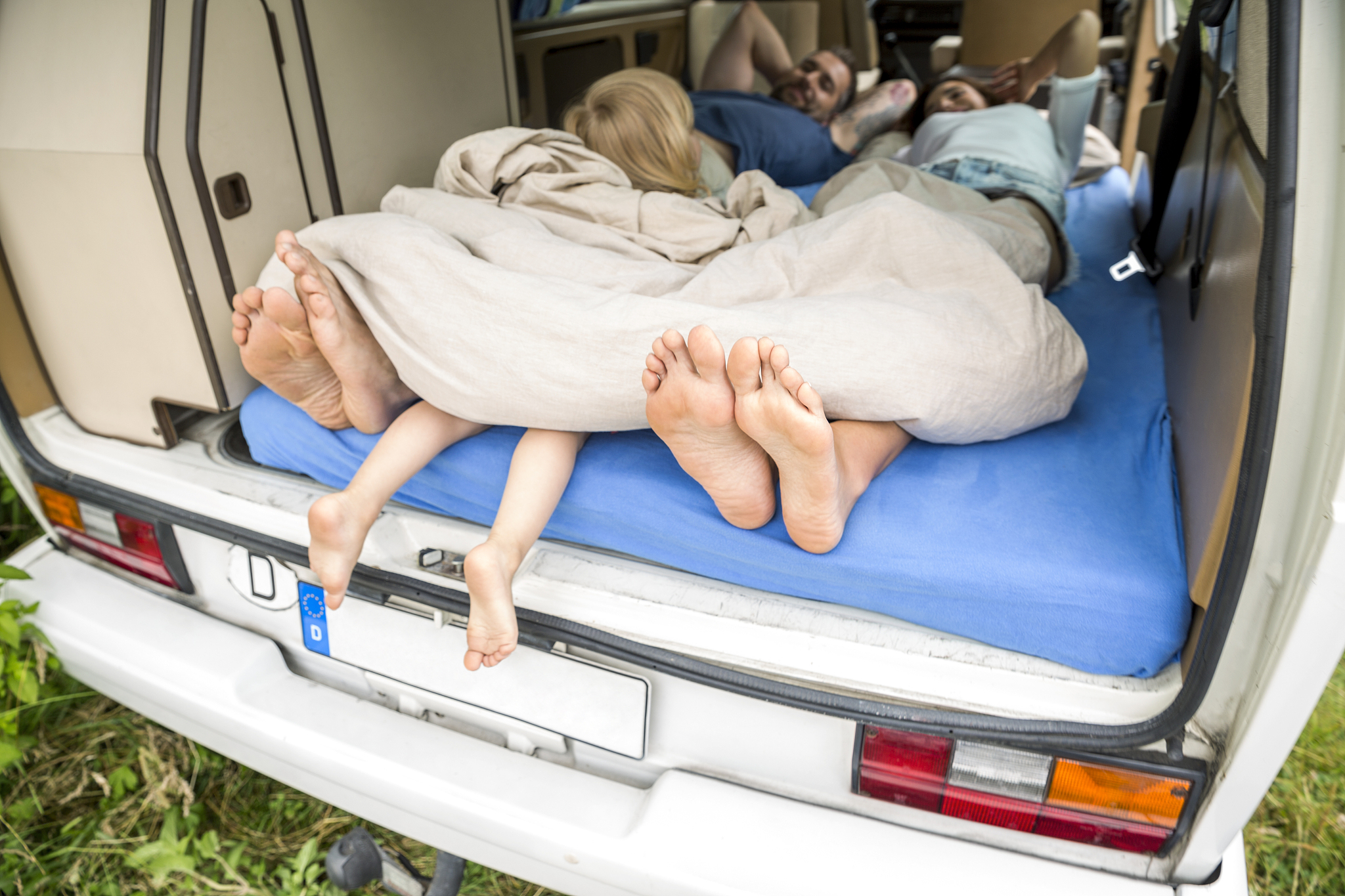 family lying on mattress in van