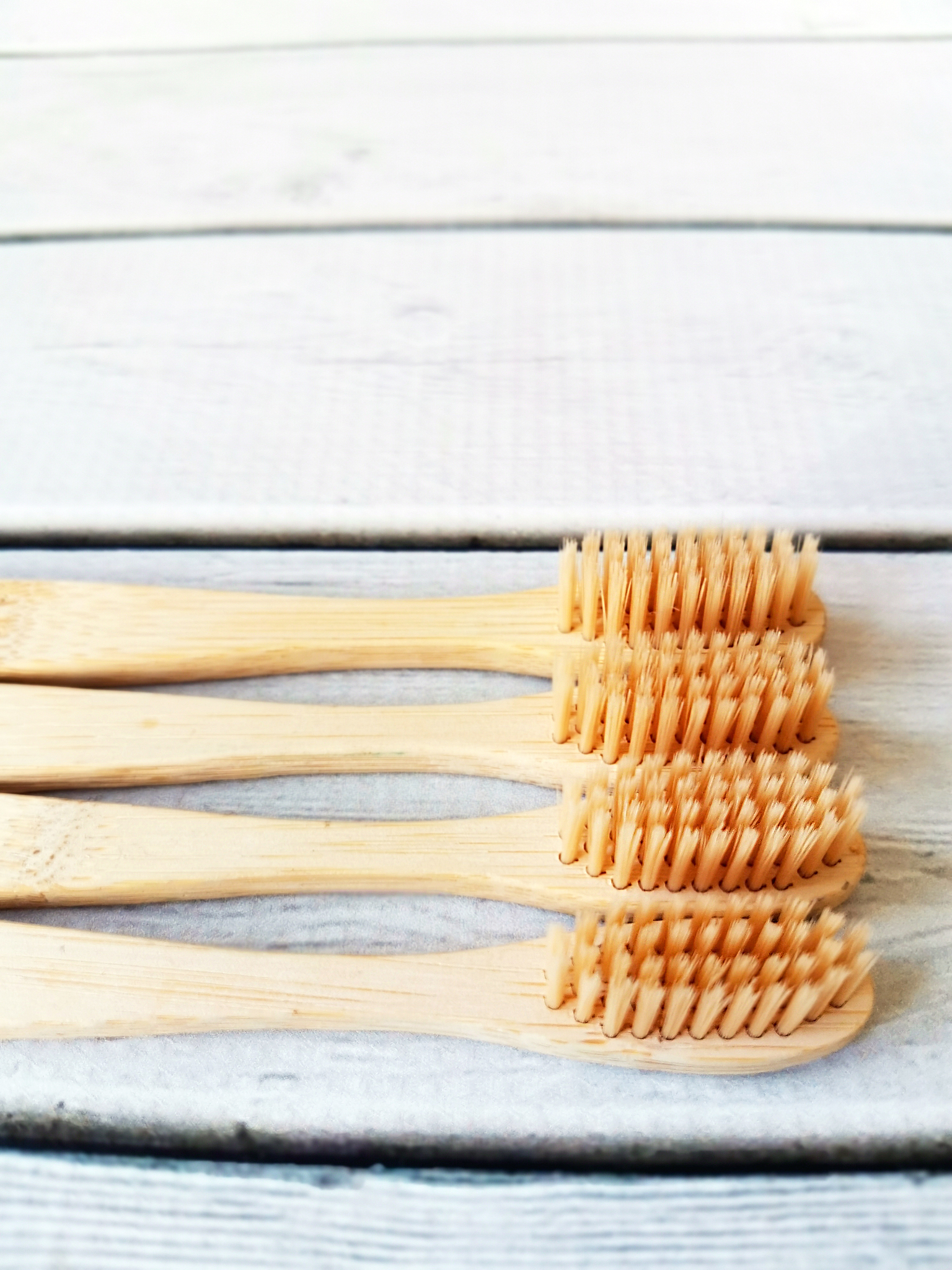 a family set of four wooden toothbrushes on white wooden backgro