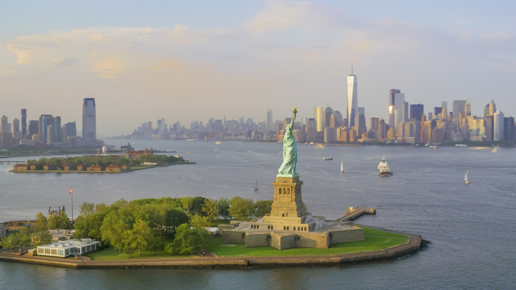 statue of liberty on liberty island at sunset with nyc in the ba