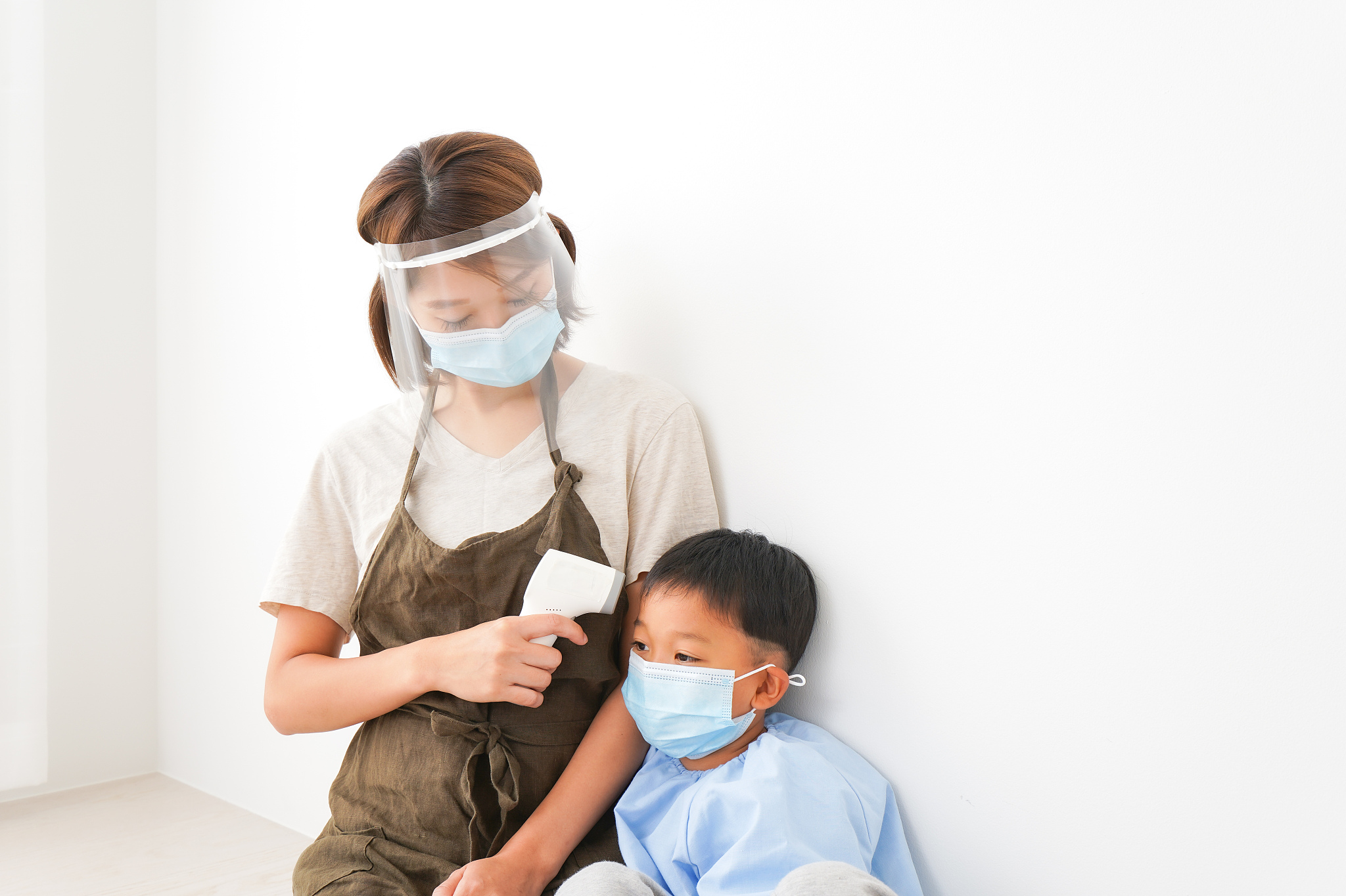 preschool teacher measuring child's body temperature