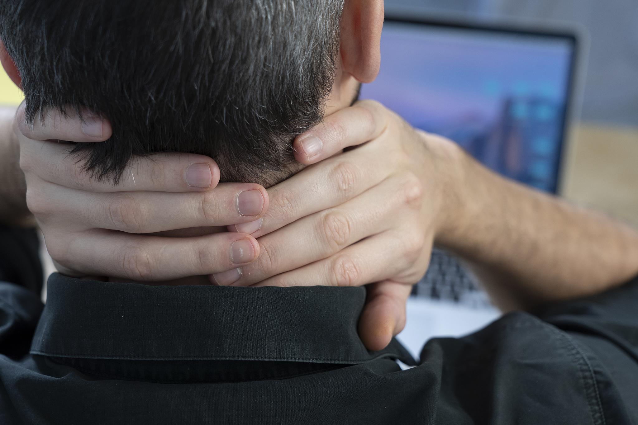 a man at his desk with neck pain.