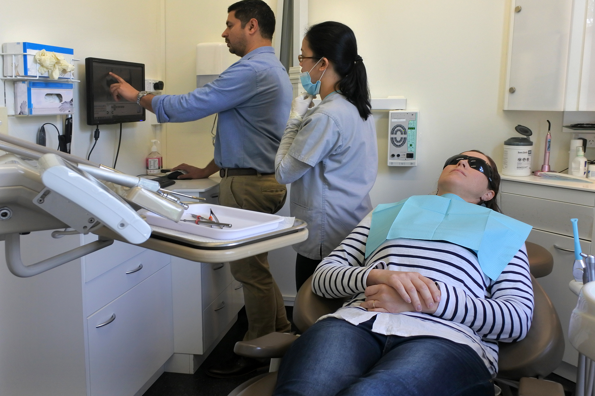 dentist and dental assistance examining teeth of a patient