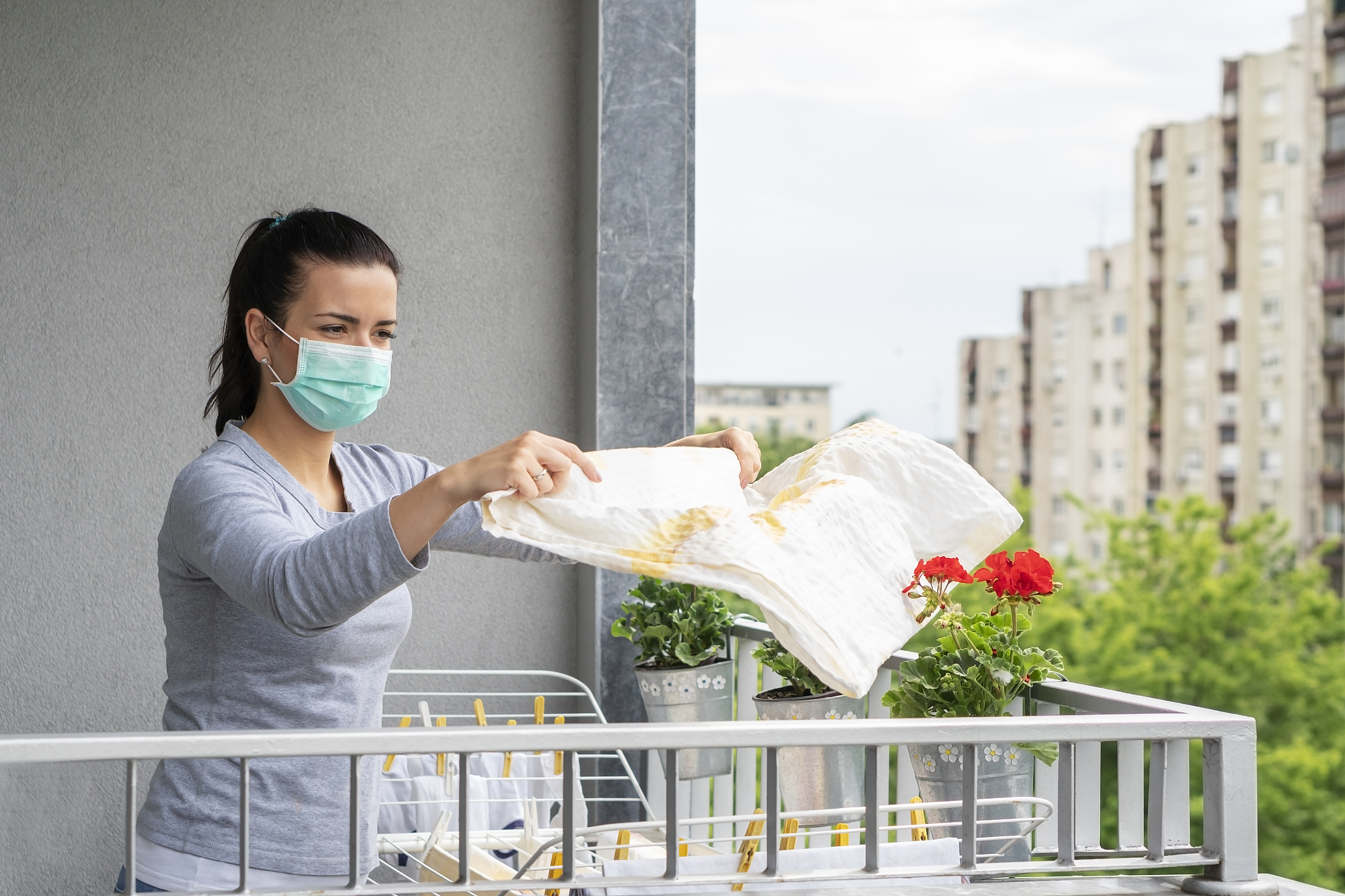 young woman with allergy hanging wet clothes to dry  on balcony