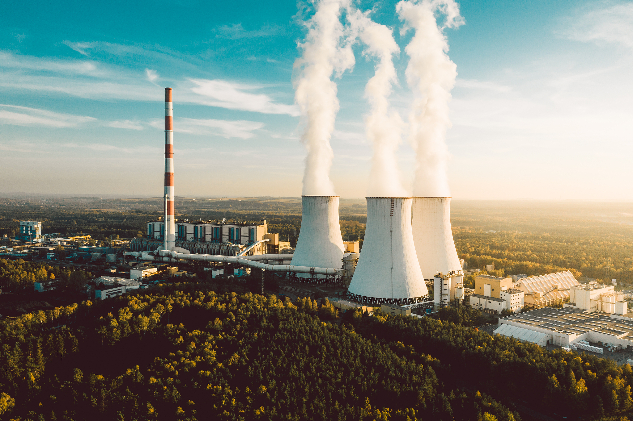 a power plant with white smoke over it's chimneys