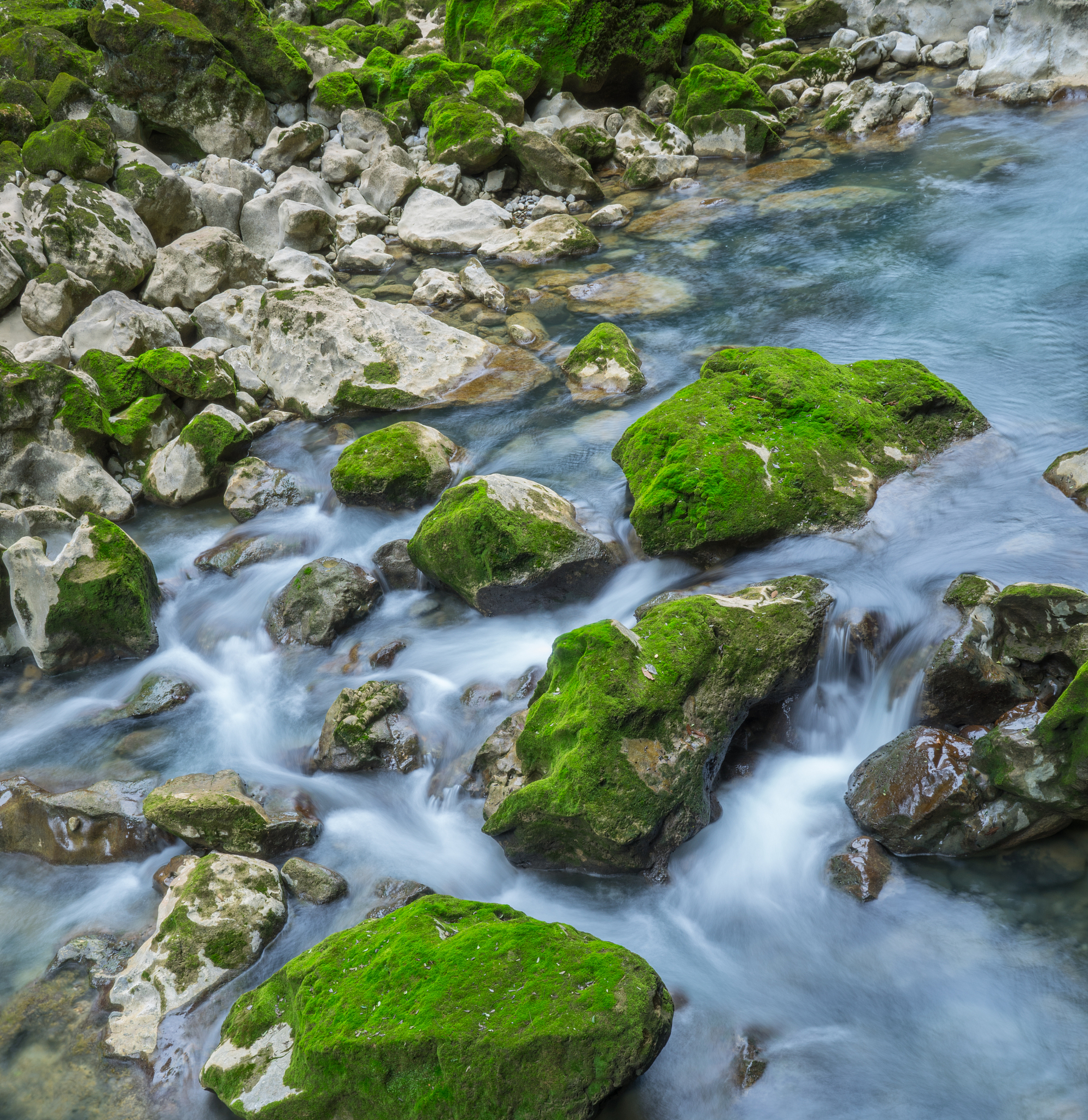 请用100字描述山清水秀小溪流水潺潺经过岩石的场景