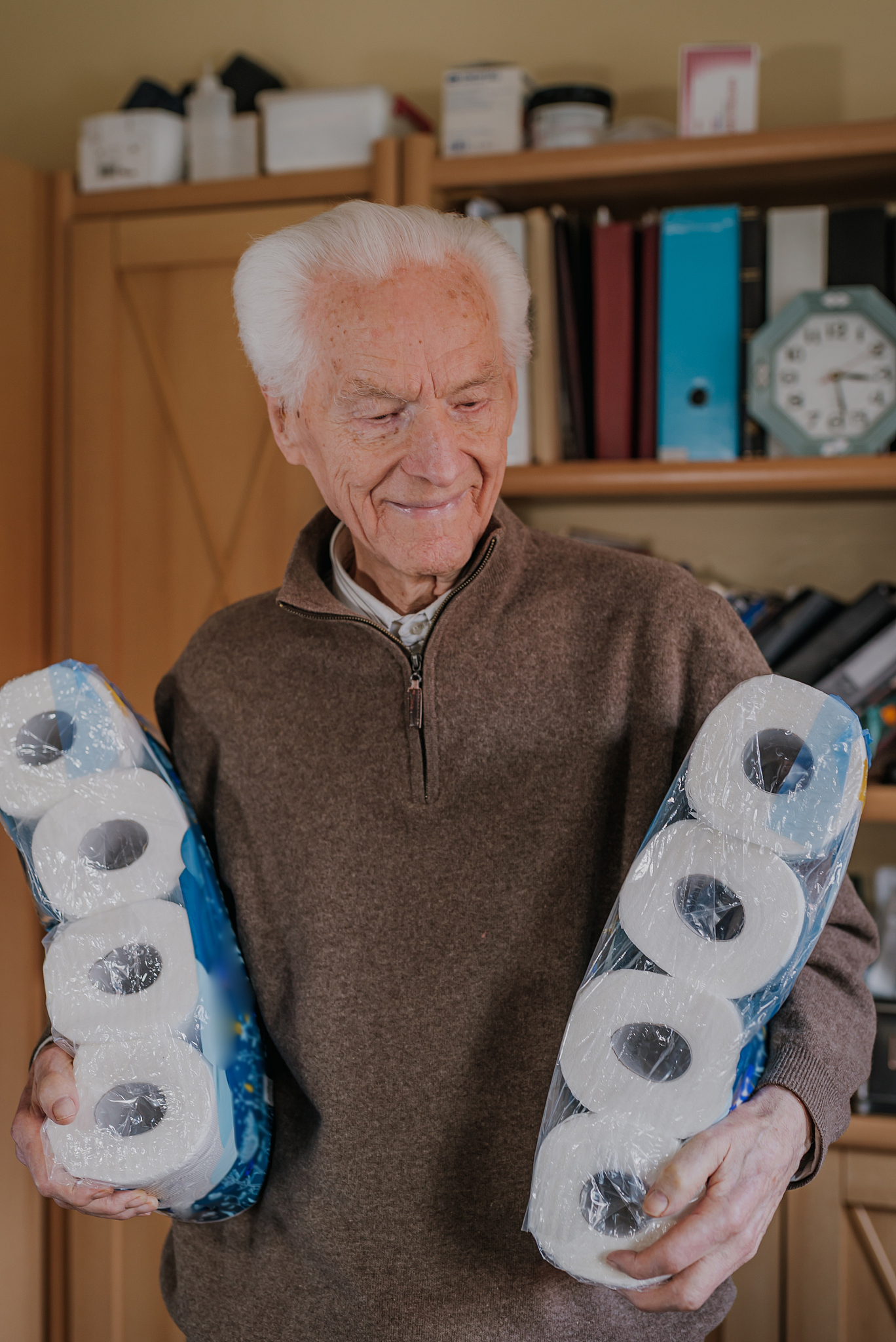 old man holding two packs of toilet paper