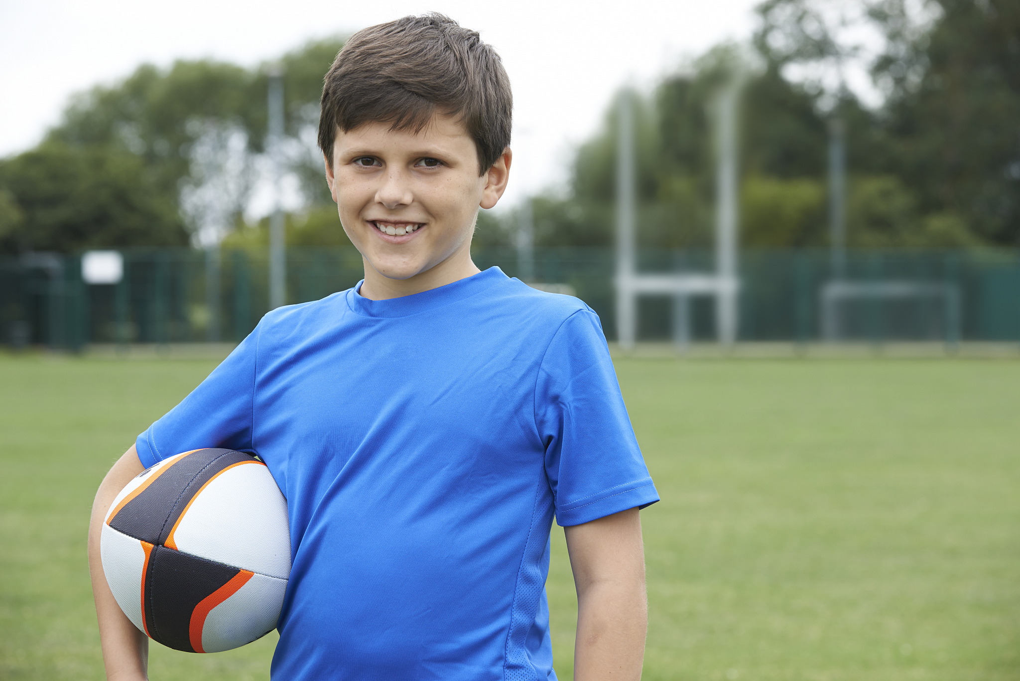 portrait of boy holding ball on school rugby pitch