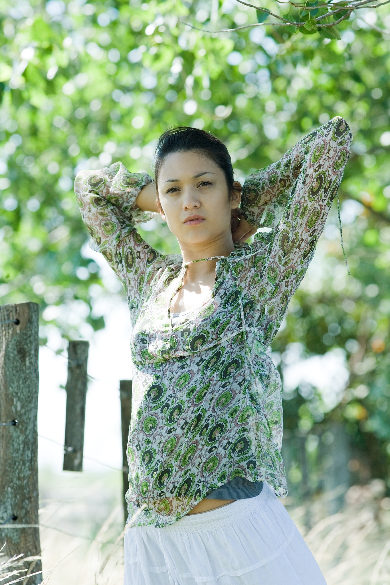 young woman standing in rural setting, hands behind head