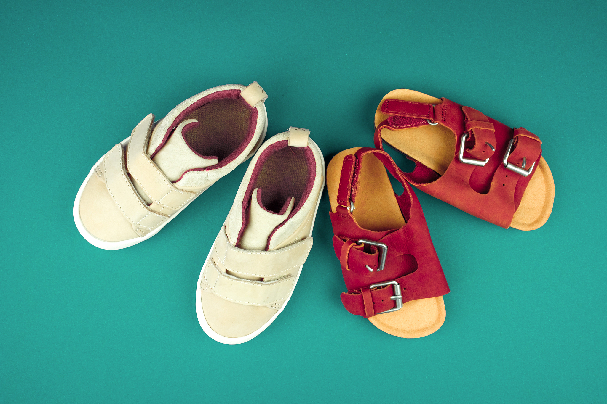 sneakers and sandals on a green background, top view, summer sho