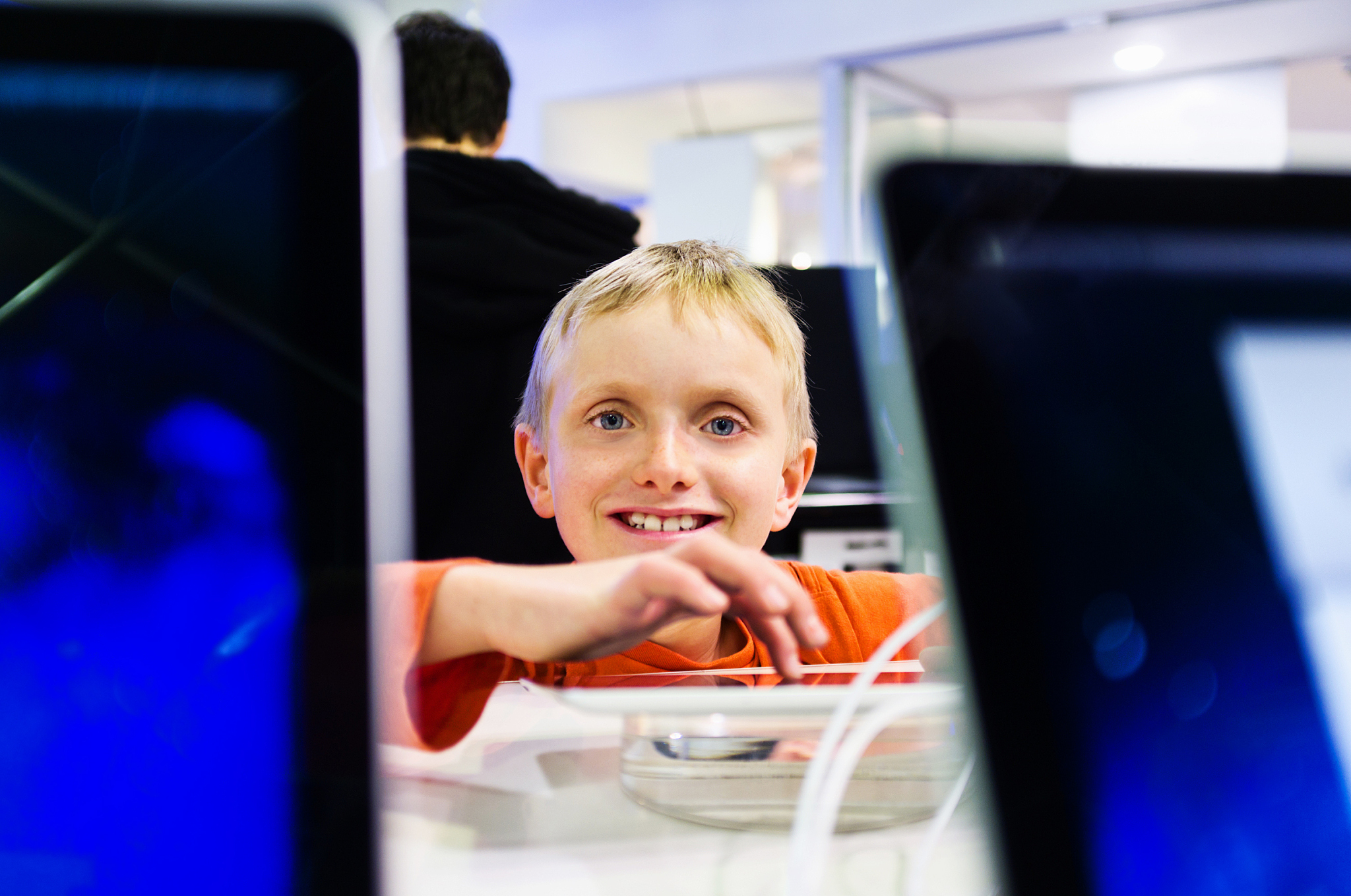 smiling boy looks up from touch screen in computer store
