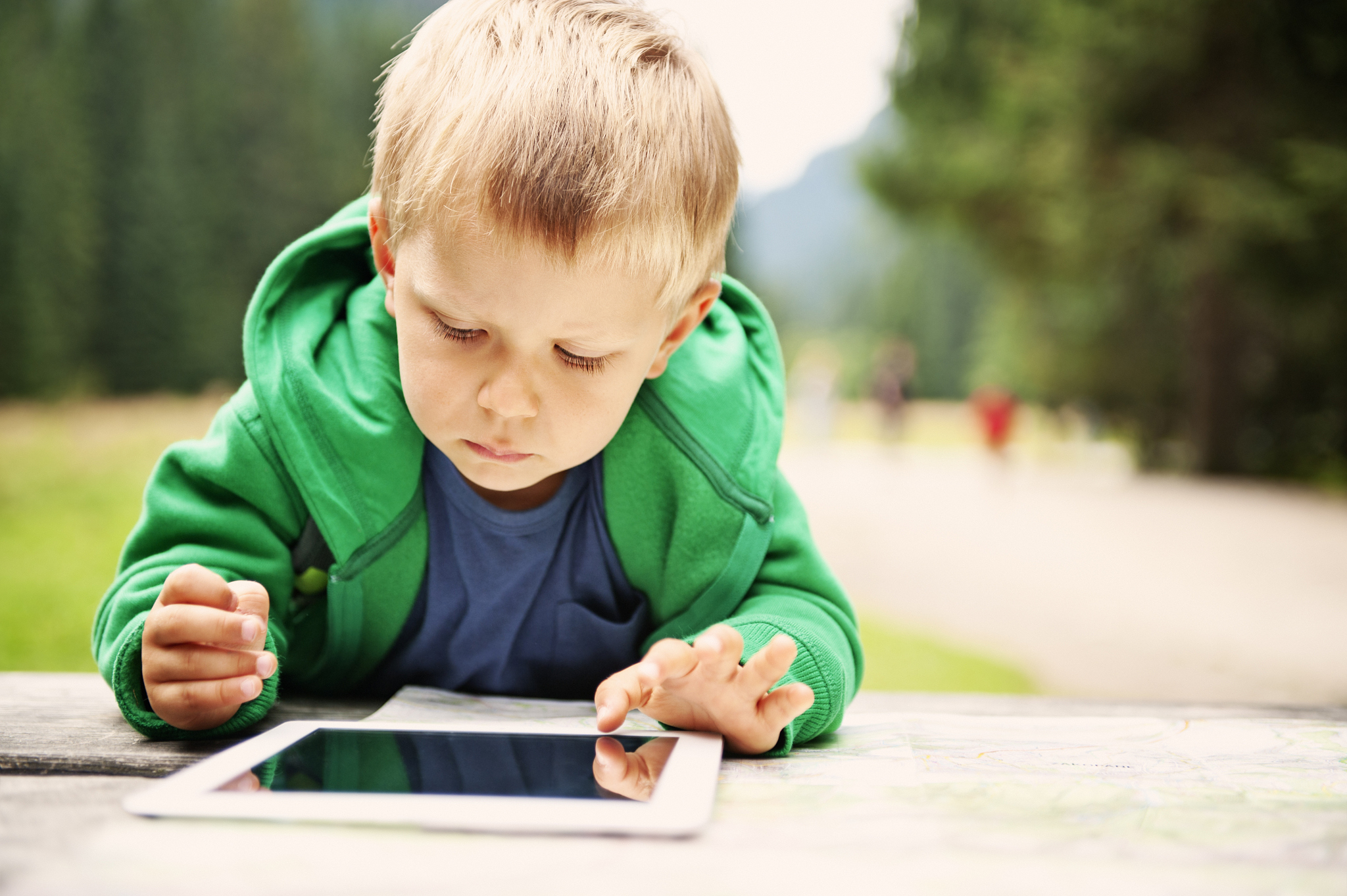 little boy checking directions on digital tablet and map.