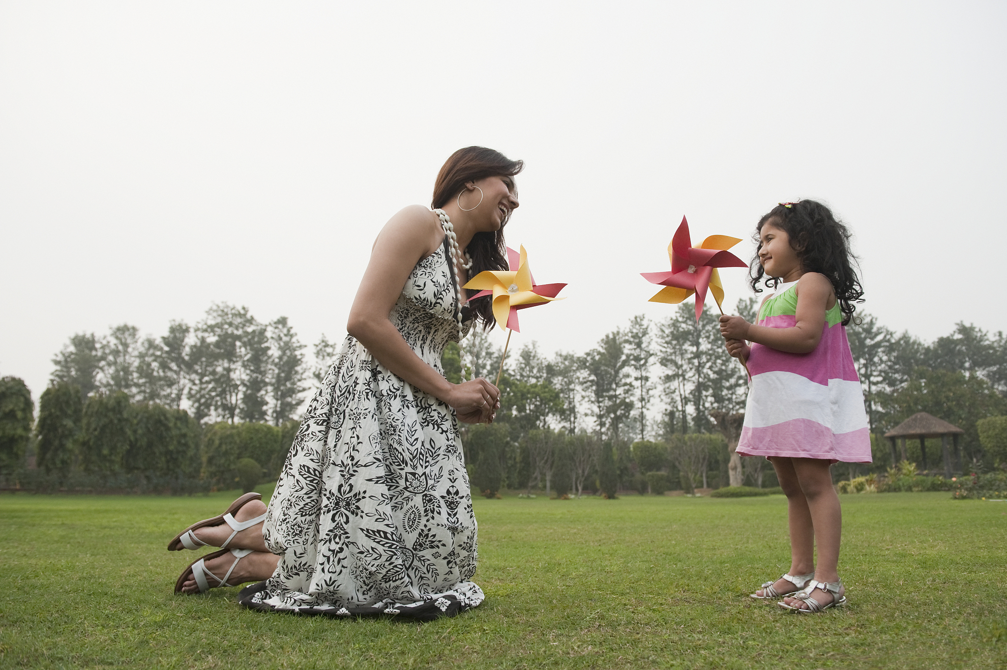 woman with her daughter playing with pinwheels in a park