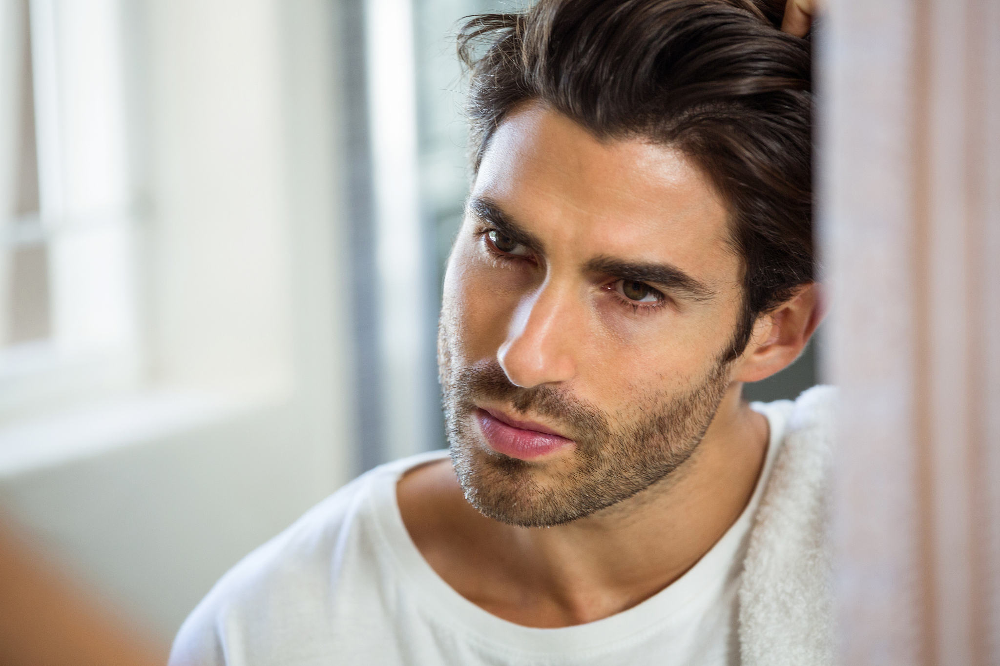 man checking his hair in mirror