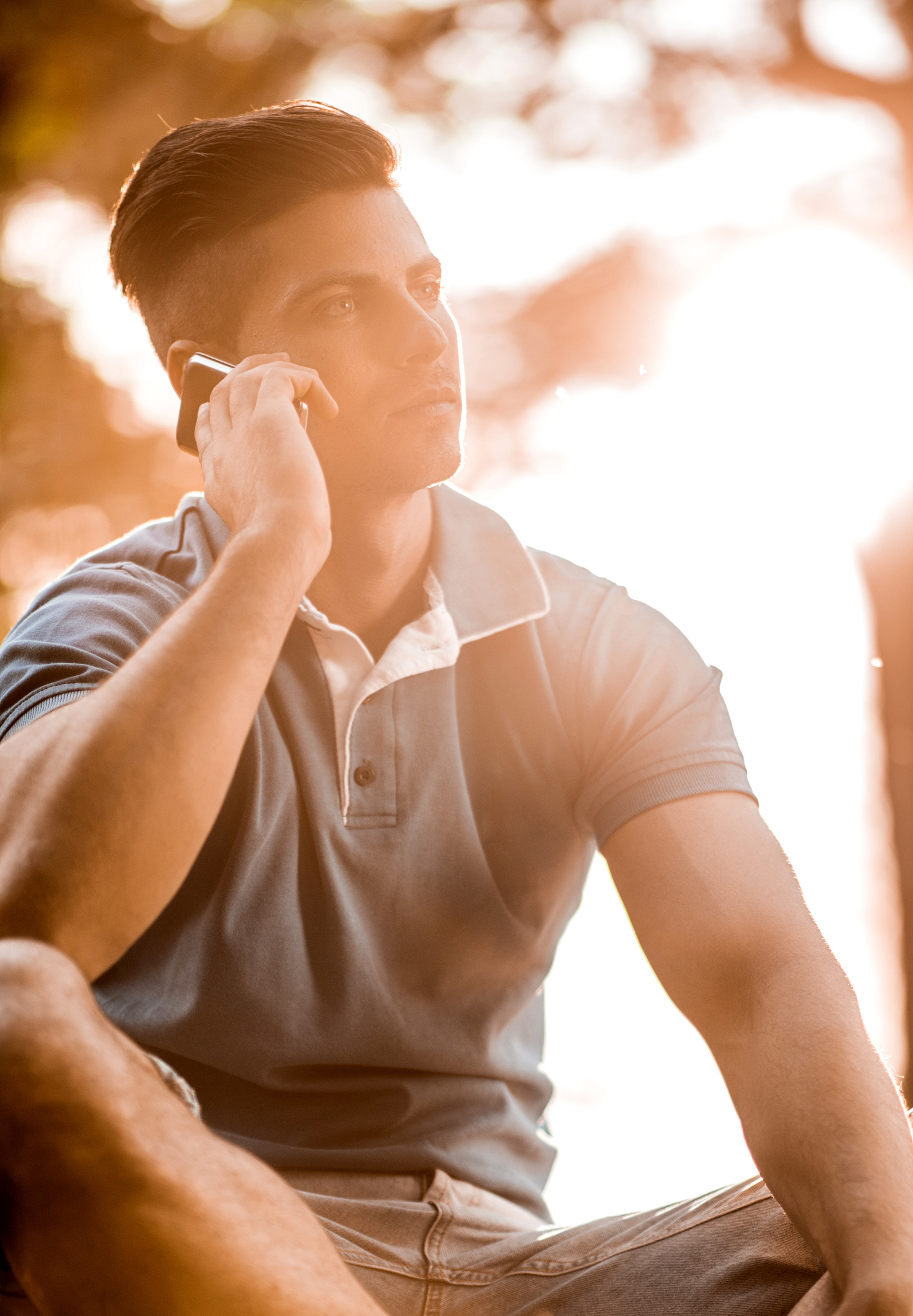 young man relaxing at sunset and talking on cell phone.