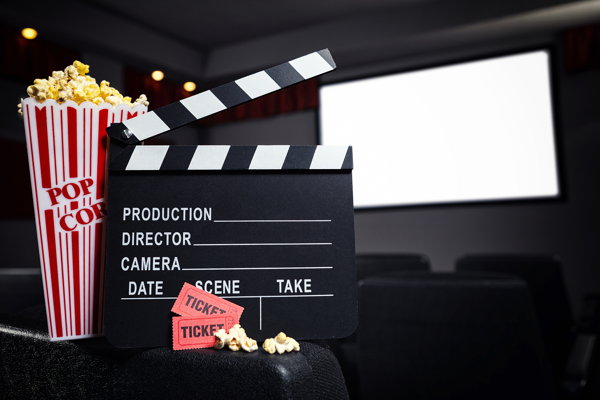 popcorn, movie tickets and film slate in theater