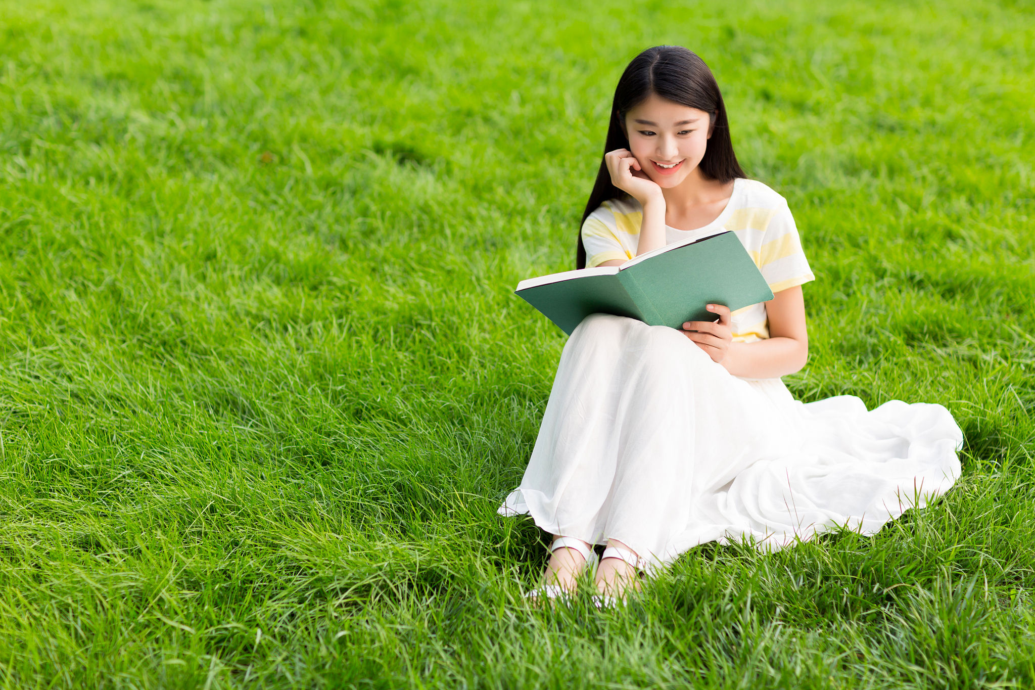 一个坐在草地上的长发女孩蓝天白云