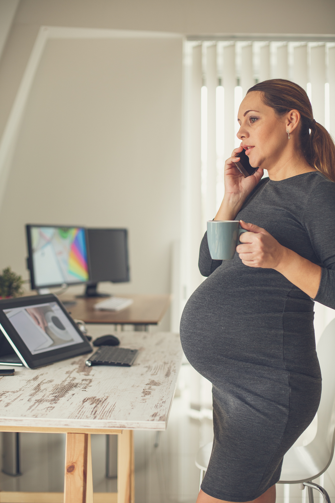 pregnant woman talking on cellphone in office