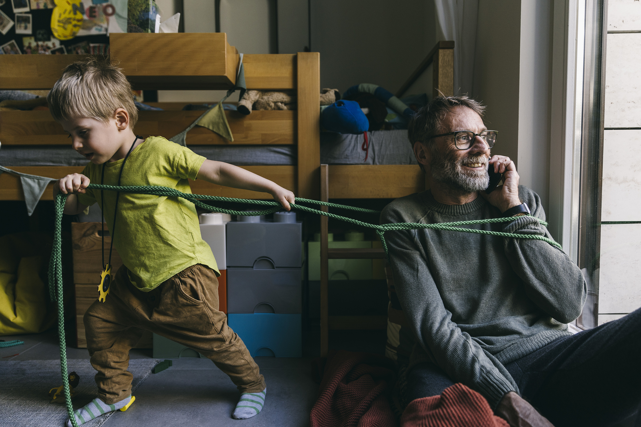 little boy pulling his father speaking  on phone