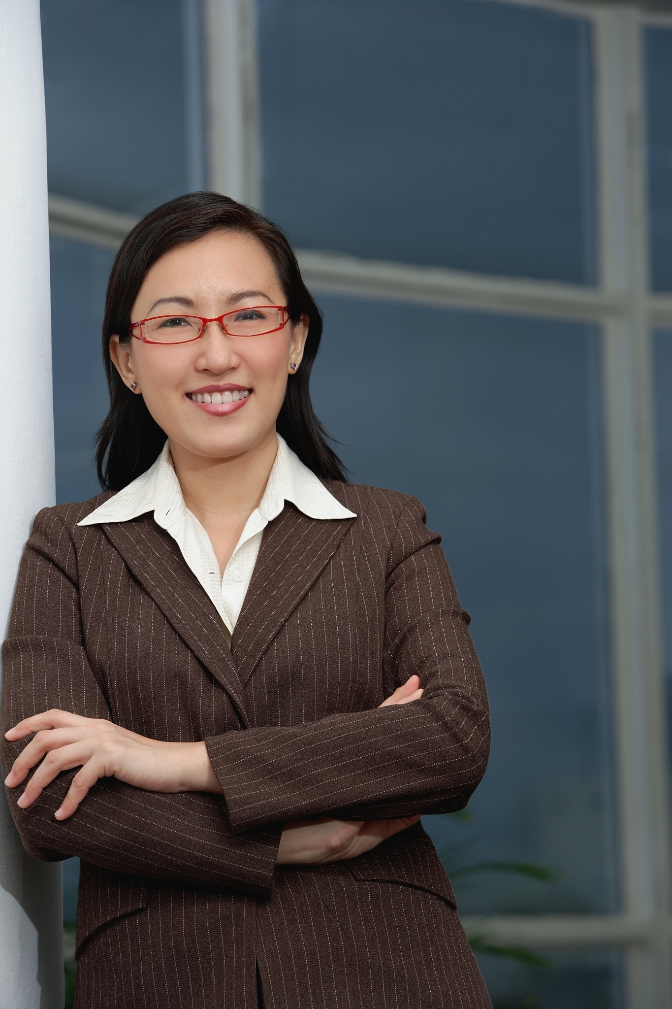 businesswoman leaning on wall, arms crossed, smiling