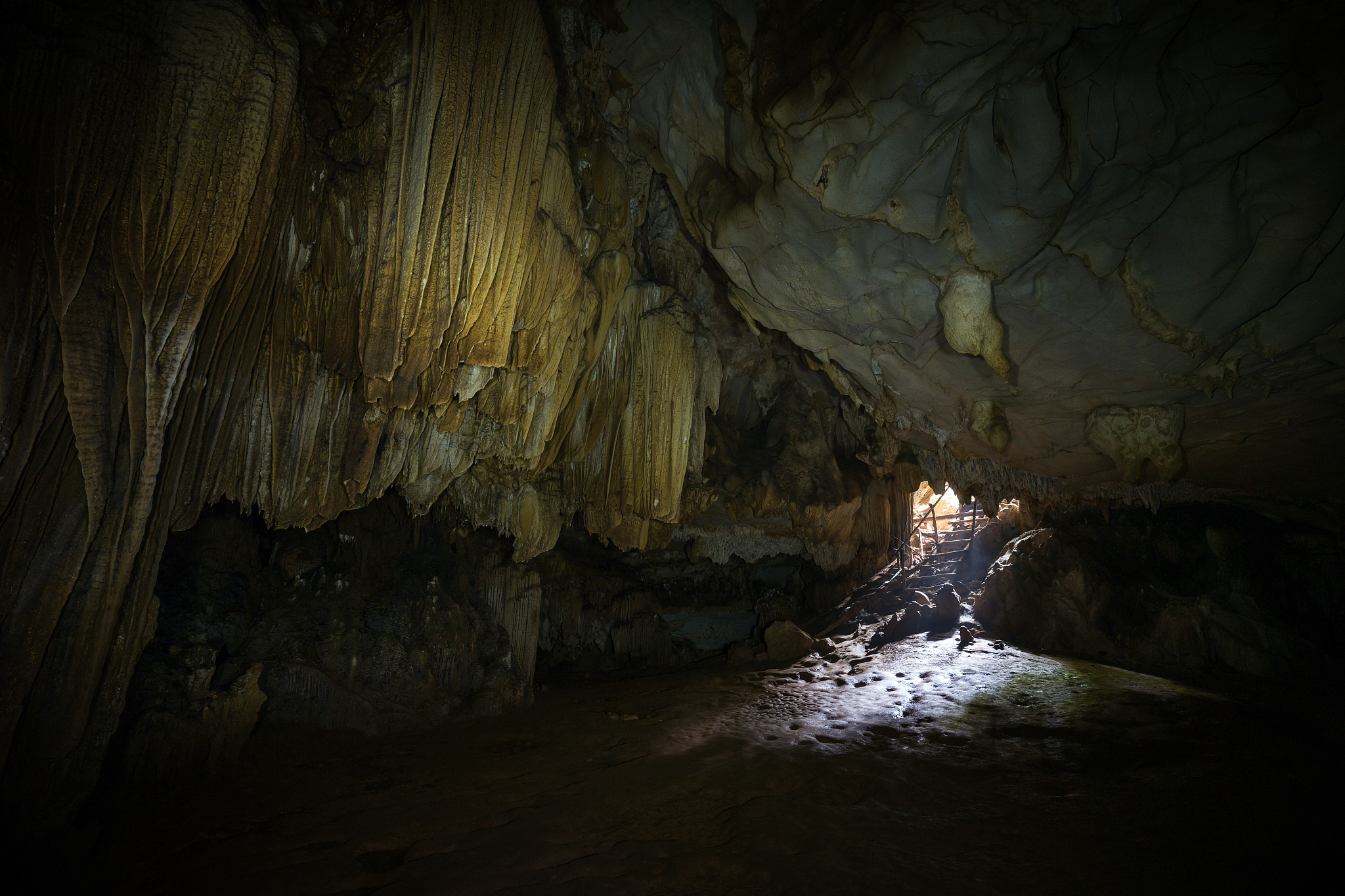 stalactites, stalagmites and mouth at the dark tham loup cave ne