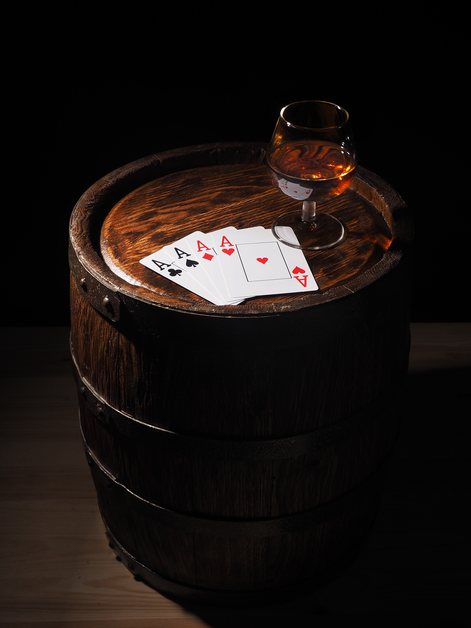 playing cards and wine glass of cognac on barrel