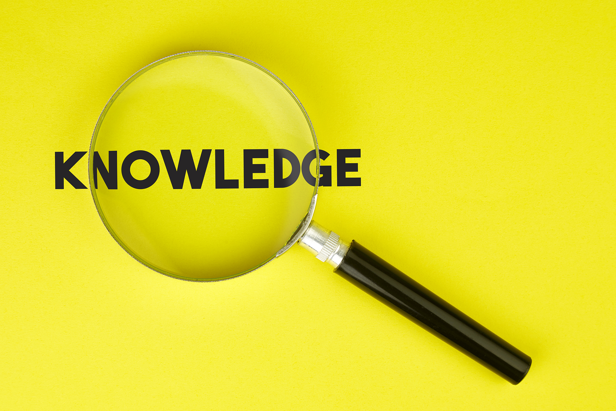 magnifier and knowledge text on yellow background stock photo