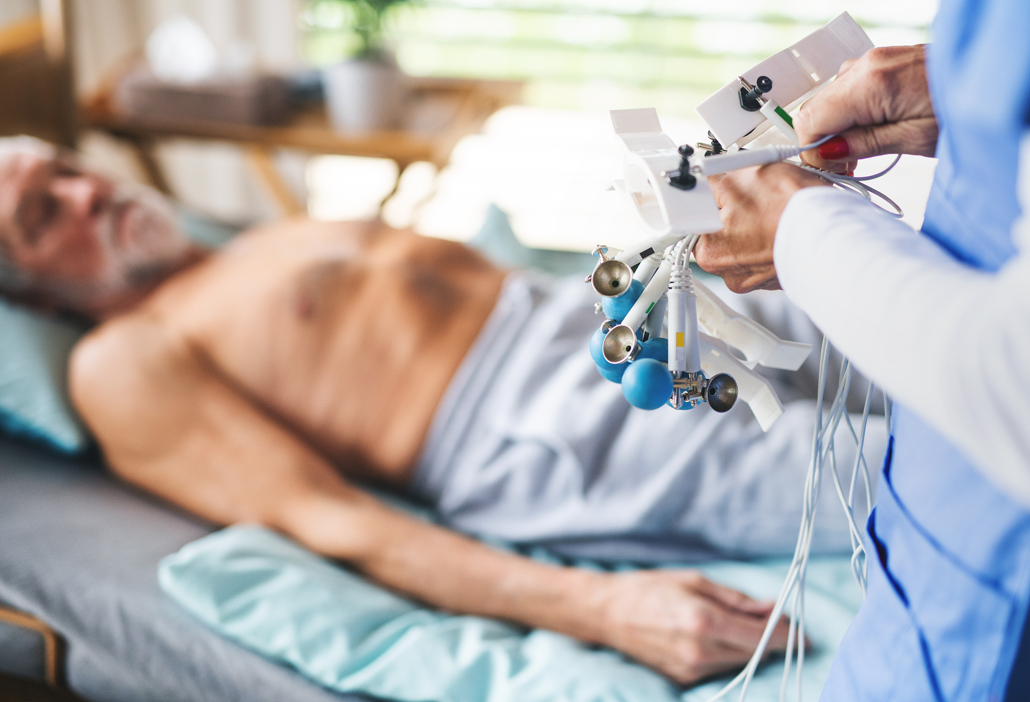 unrecognizable nurse looking after senior patient in bed in hosp