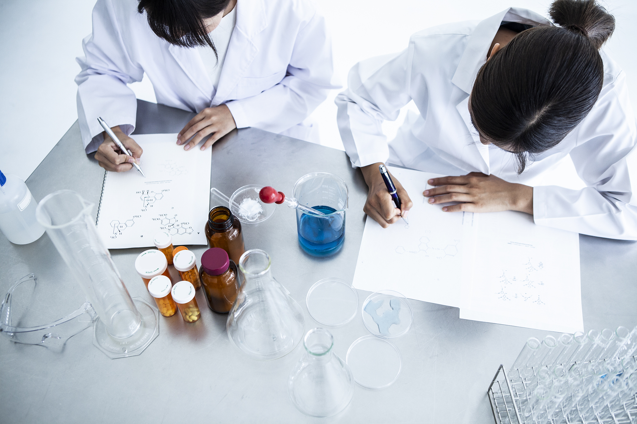 a woman working in a white coat is writing.
