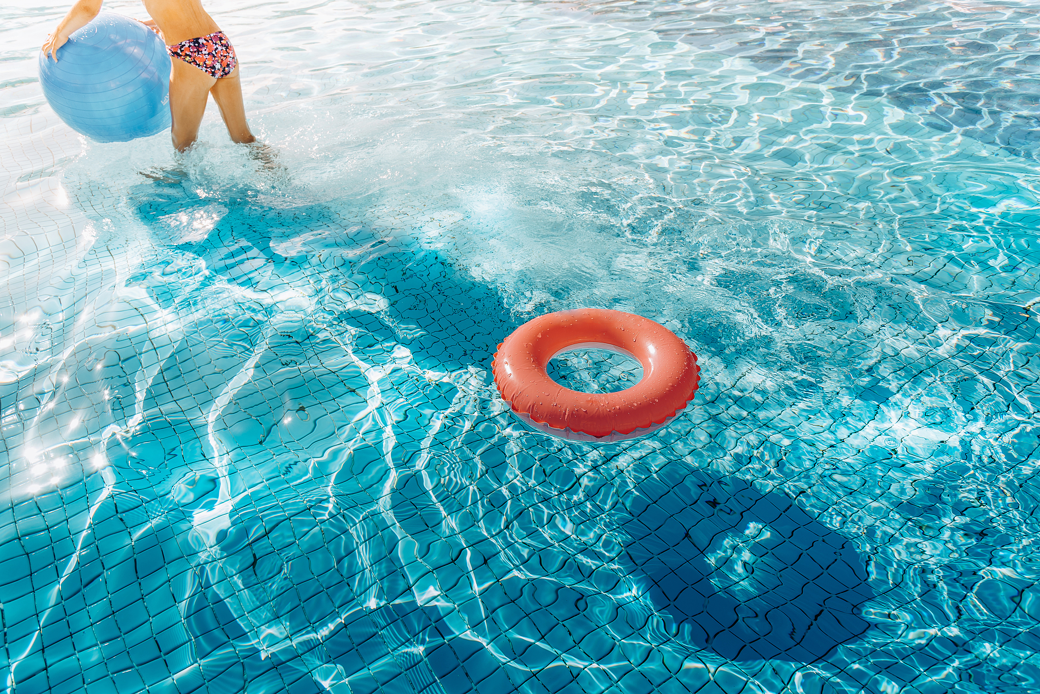 orange swim ring  and teenage girl with ball in  pool
